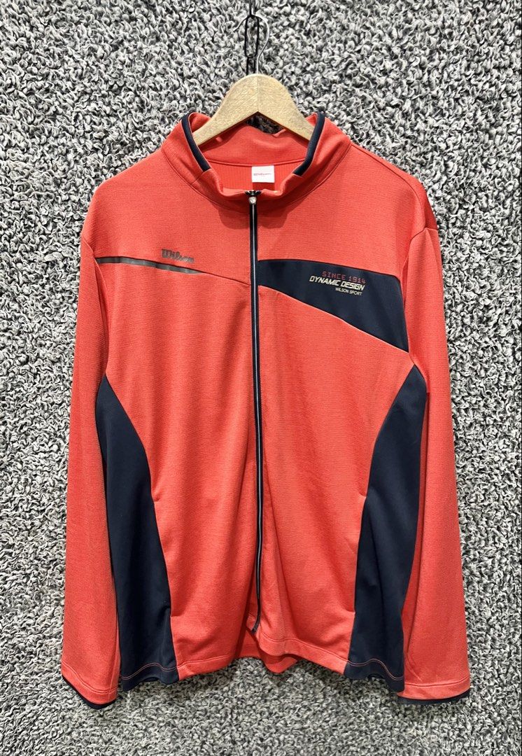 Wilson Sport "Dynamic Design" Full-Zip Track Jacket. | Size XL (Category: Coats, Jackets and Outerwear) located in General Trias. Submitted by zrchustle.604 (Listing ID 1466970478, Image 2). Description: Wilson Sport "Dynamic Design" Full-Zip Track Jacket. This functional training zip-up features a red body accented with dark navy/black geometric side paneling and chest overlays, complete with the text "Since 1914 Dynamic Design Wilson Sport" on 