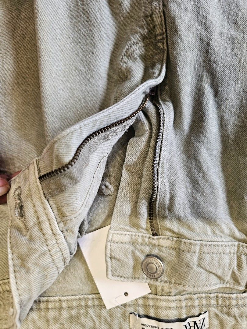 Zara denim Shorts (Category: Shorts) located in Baguio. Submitted by kayeonlineshop (Listing ID 1466870389, Image 3). Description: Zara men's regular fit denim shorts featuring a classic five-pocket design, copper-tone rivets, and a mid-waist cut. The fabric has a distinctive washed-effect finish with a subtle grey-green or light khaki-tinted hue w36l18h21.