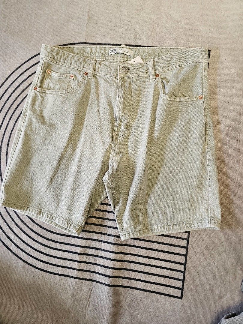 Zara denim Shorts (Category: Shorts) located in Baguio. Submitted by kayeonlineshop (Listing ID 1466870389, Image 1). Description: Zara men's regular fit denim shorts featuring a classic five-pocket design, copper-tone rivets, and a mid-waist cut. The fabric has a distinctive washed-effect finish with a subtle grey-green or light khaki-tinted hue w36l18h21.