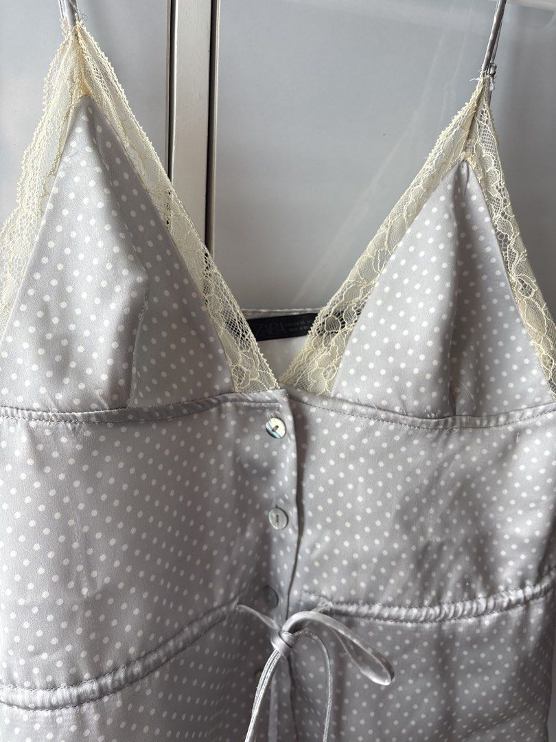 Zara Polka Dot Satin Camisole Top (Category: Sleeveless) located in Manila. Submitted by jodi.declutters (Listing ID 1466784321, Image 2). Description: - Brand: Zara - SRP 1995 - Size: XS (Made in Morocco) - Material & Design: Grey satin with all-over white polka dots - Details: Cream lace trim on V-neckline, button front placket, and adjustable waist drawstring - Straps: Thin spaghetti straps - Condition: Excellent / Like new - Perfect for layer