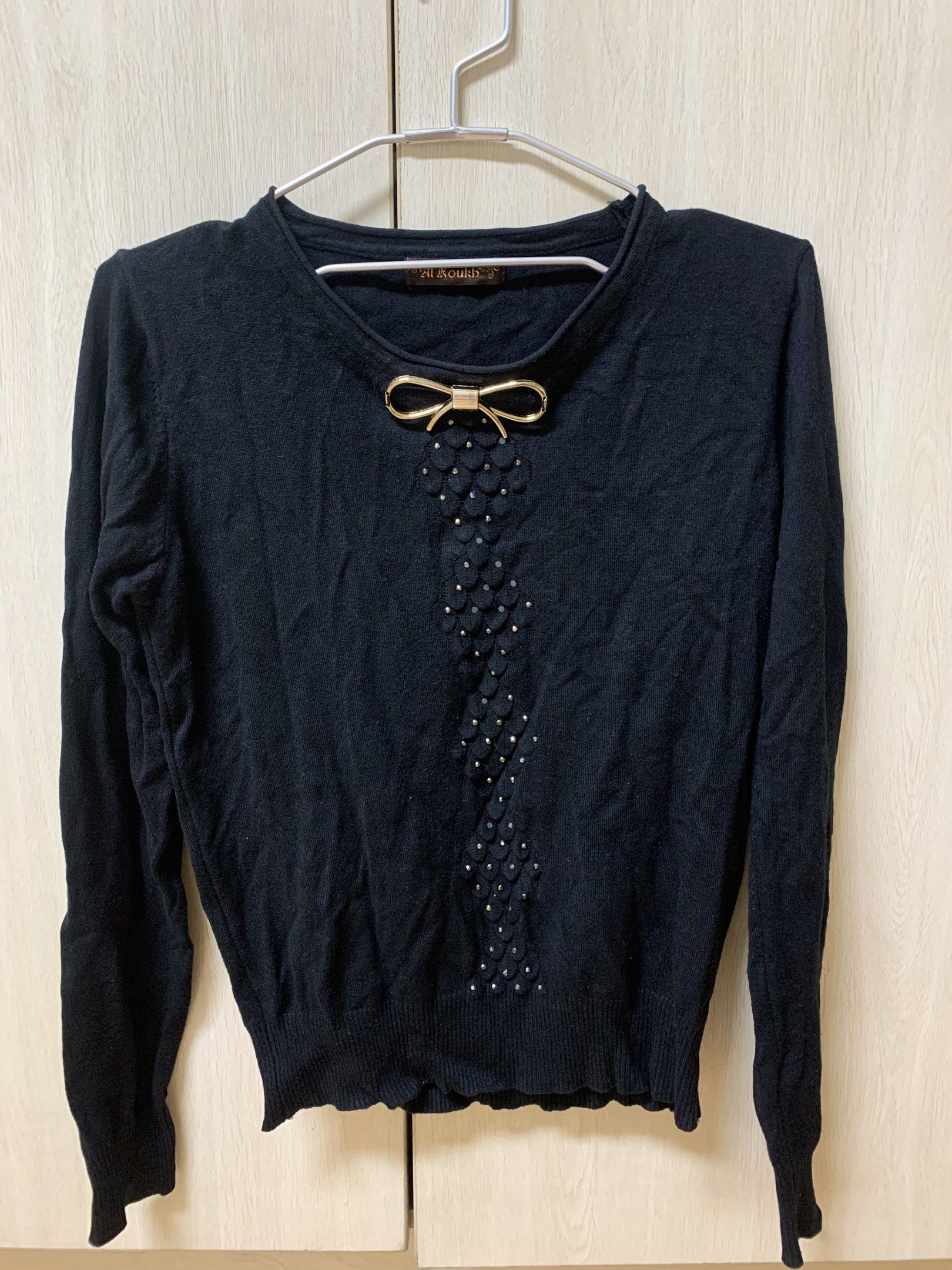 Al Koukh Black Embellished Sweater (Category: Coats, Jackets and Outerwear) located in San Juan City. Submitted by andyria (Listing ID 1419137779, Image 1). Description: - Al Koukh black sweater - Round neckline - Long sleeves - Gold bow and embellished front details - Ribbed hem and cuffs - Brand tag at the back.