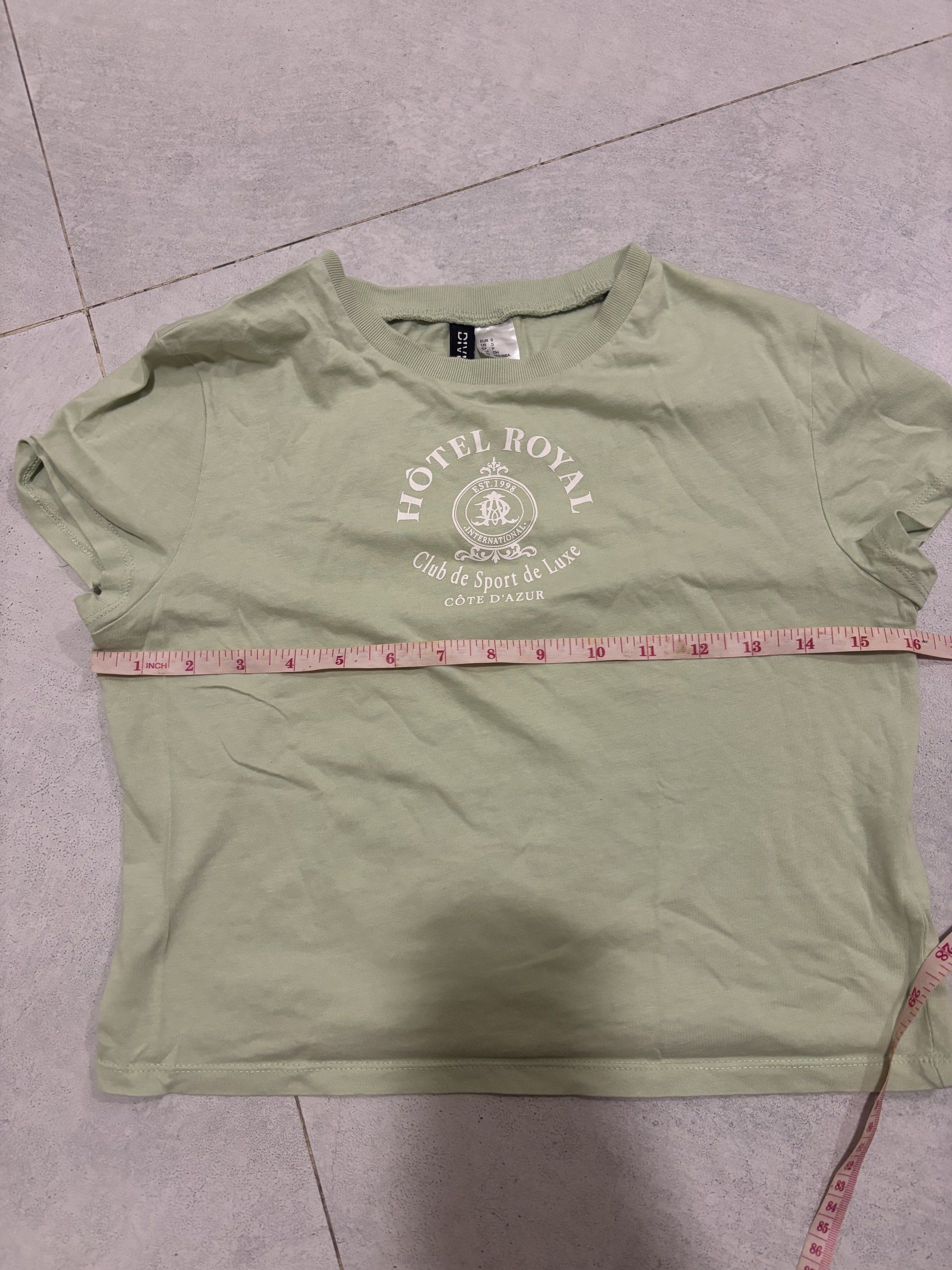 H&M Hotel Royal Crop Top (Category: Shirts) located in Manila. Submitted by nicoleaaa (Listing ID 1419009237, Image 2). Description: - H&M crop top - Features a 'Hotel Royal' graphic - Color: Light green - Short sleeves - Crew neck - Length: Approximately 18 inches - Width: Approximately 15 inches.
