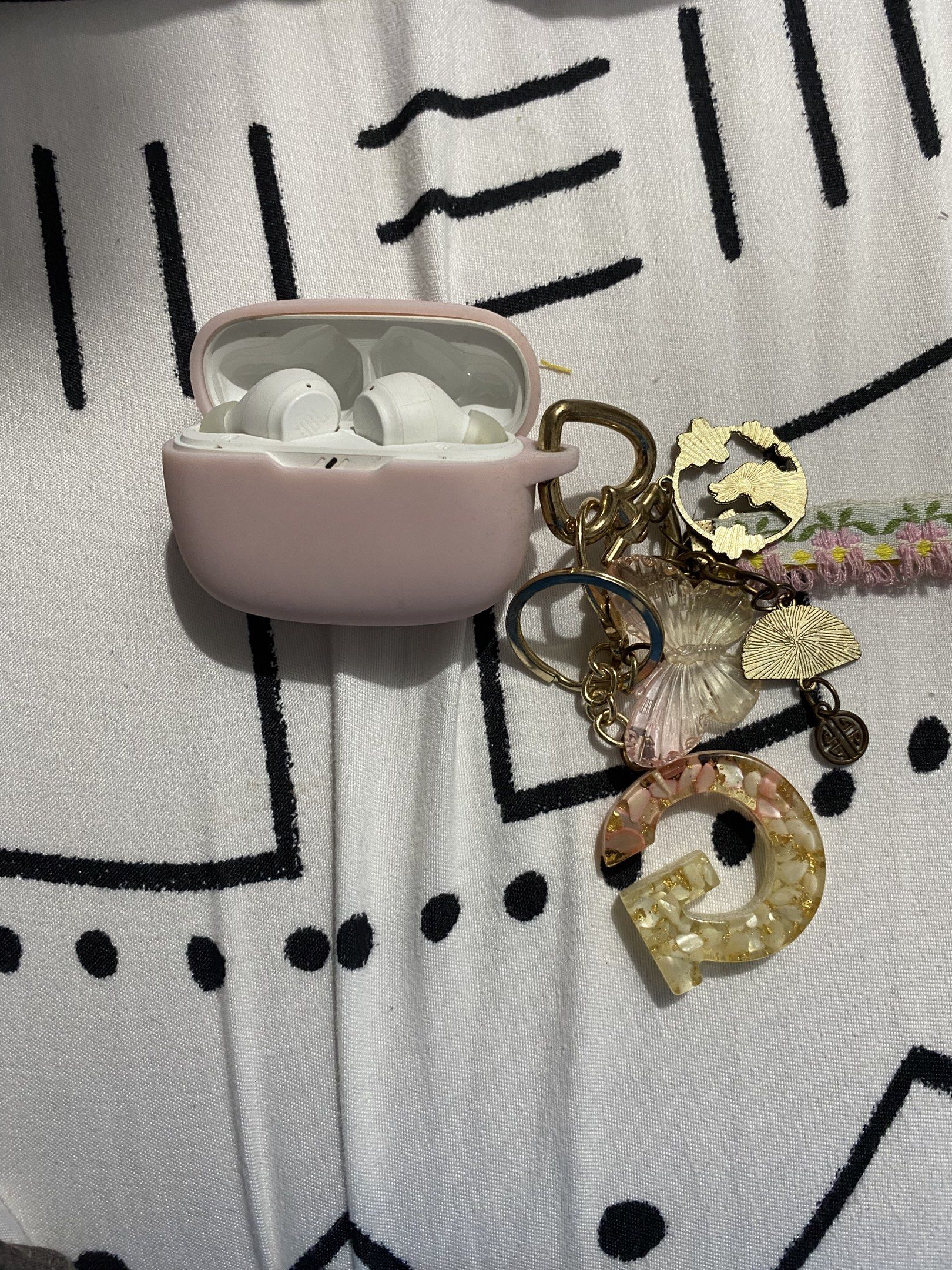 JBL Earbuds with Case (Category: Earphones) located in Manila. Submitted by glads_closet (Listing ID 1419001546, Image 3). Description: - White JBL earbuds - Pink protective case with JBL logo - Includes a keychain with: - Gold-colored charm - Floral charm - Resin letter 'G'.