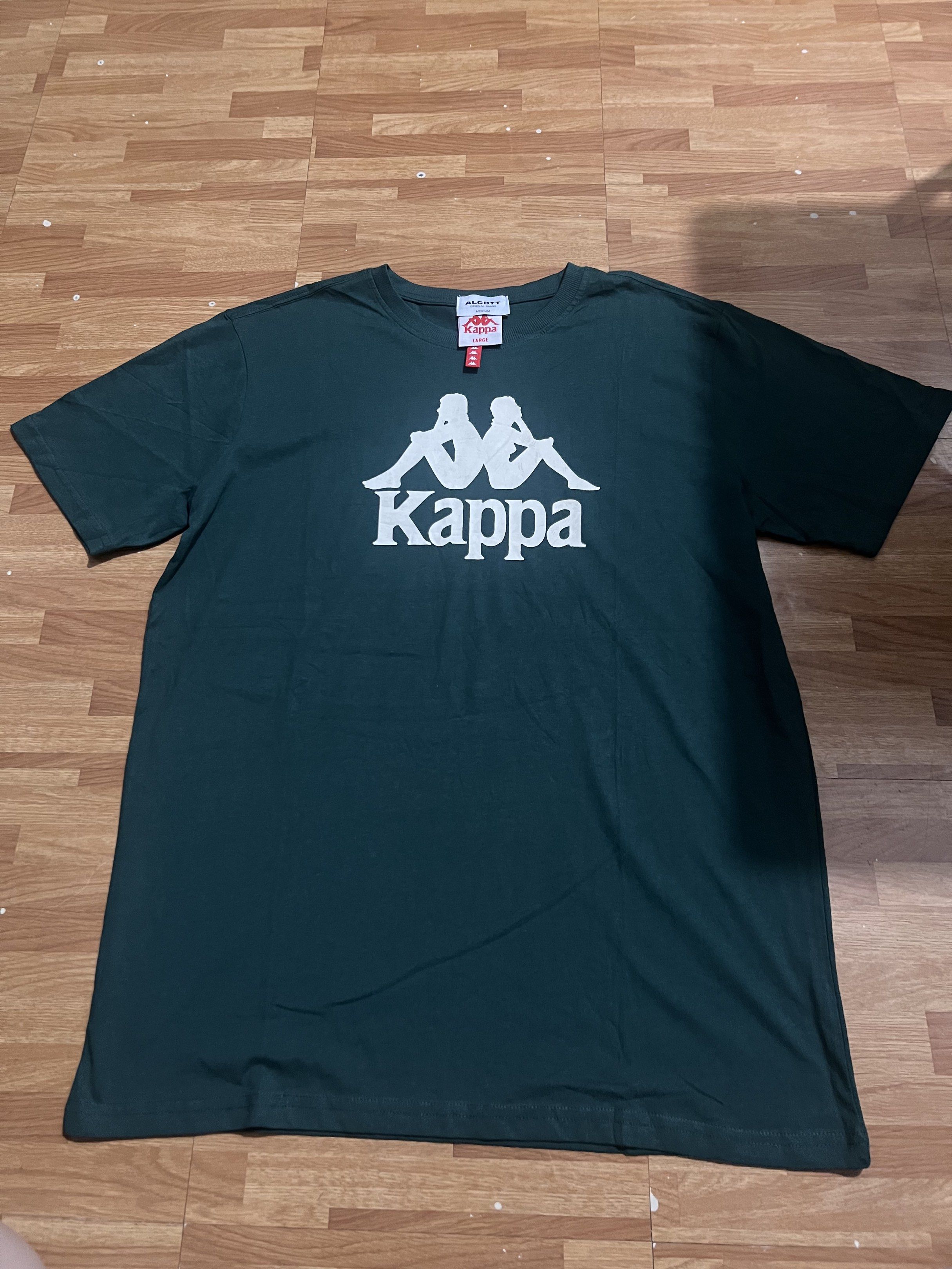 Kappa T-shirt (Category: Tshirts & Polo Shirts ) located in Makati City. Submitted by msverify (Listing ID 1419118873, Image 2). Description: - Dark green Kappa T-shirt - White Kappa logo on the front - Crew neck and short sleeves - Brand: Alcott - Available sizes: Large, Medium.