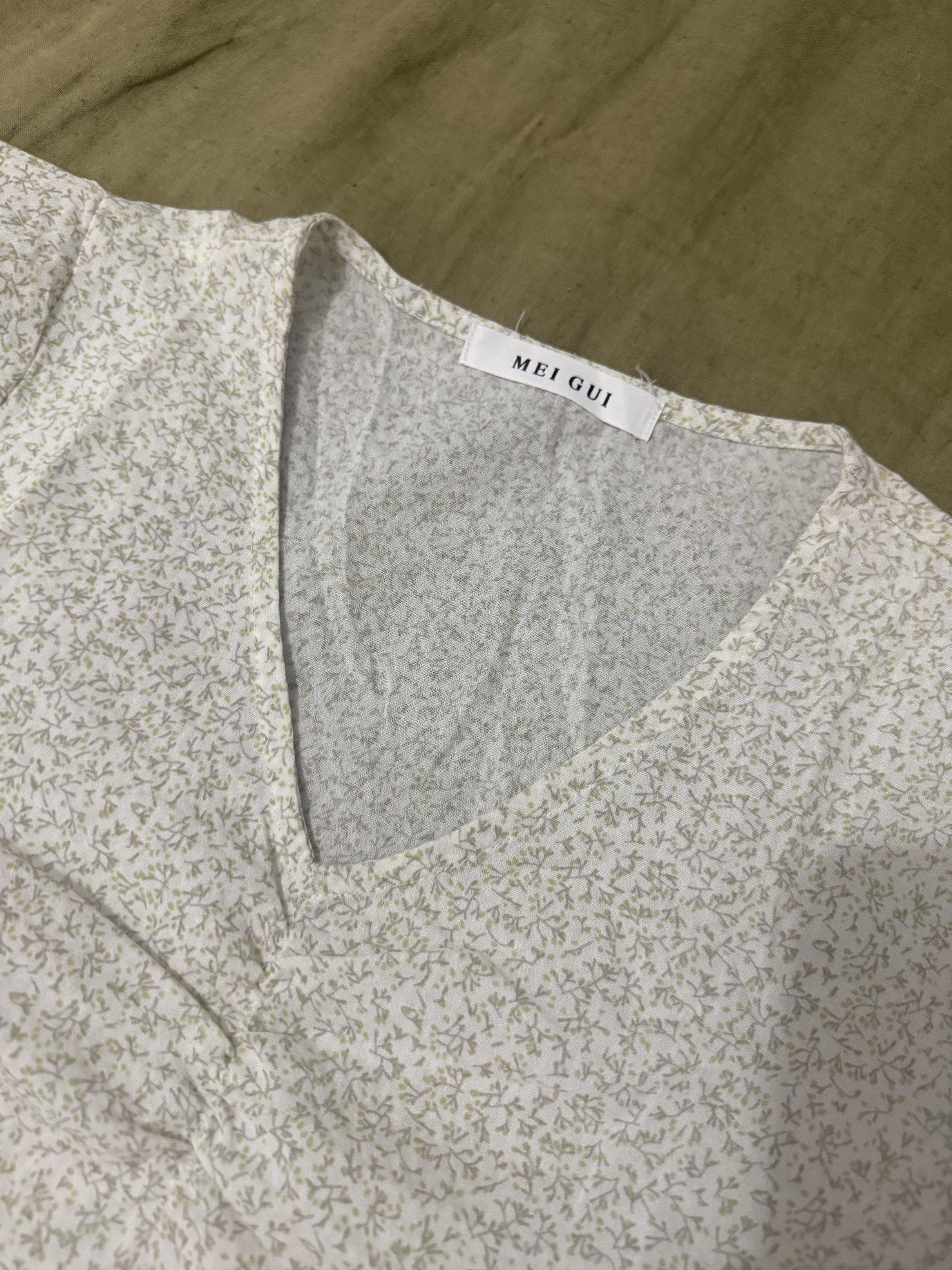 MEI GUI Floral V-Neck Blouse (Category: Blouses) located in Paranaque City. Submitted by bailey_cade (Listing ID 1419133506, Image 3). Description: Floral blouse with a V-neck design. Features short sleeves and a slightly puffed shoulder. The blouse has a delicate floral pattern in shades of white and green. The brand tag is visible. Measurements are provided in the images. Used so please manage your expectations .