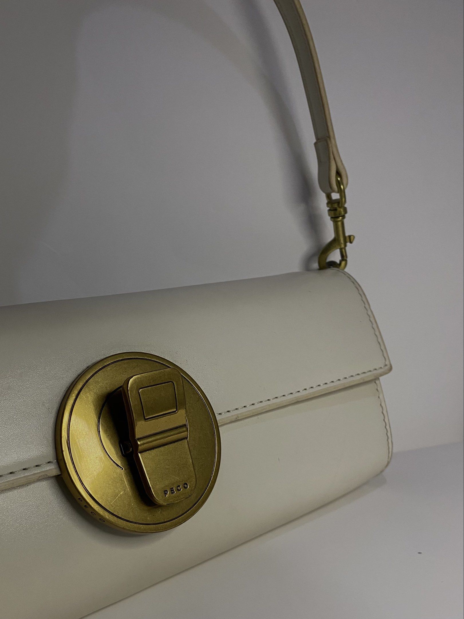 PECO White Clutch Bag (Category: Luxury Bags & Wallets) located in Manila. Submitted by unodostresss123 (Listing ID 1419127943, Image 2). Description: - White shoulder/clutch bag - Gold-tone clasp - Detachable strap - Shoulder or Clutch - Smooth material (possibly leather-like) - PECO logo on clasp.