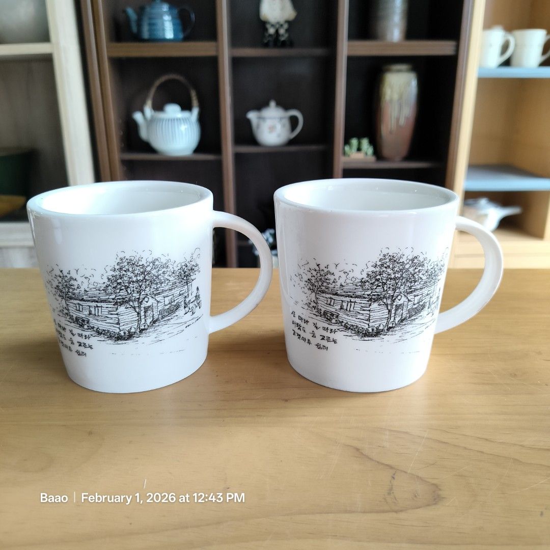 White Ceramic Mug with Illustration (Category: Coffee & Tea Tableware) located in Baao. Submitted by all.things.japan (Listing ID 1419016822, Image 1). Description: COUPLE ART MUGS - Set of two white ceramic mugs - thicker than standard mugs - Features black and white illustrations of houses and trees - Simple, rounded design with handles - Clean and ready for use - Ideal for coffee, tea, and other beverages - 3.75 inches (h) x 3.6 inches (d) Min