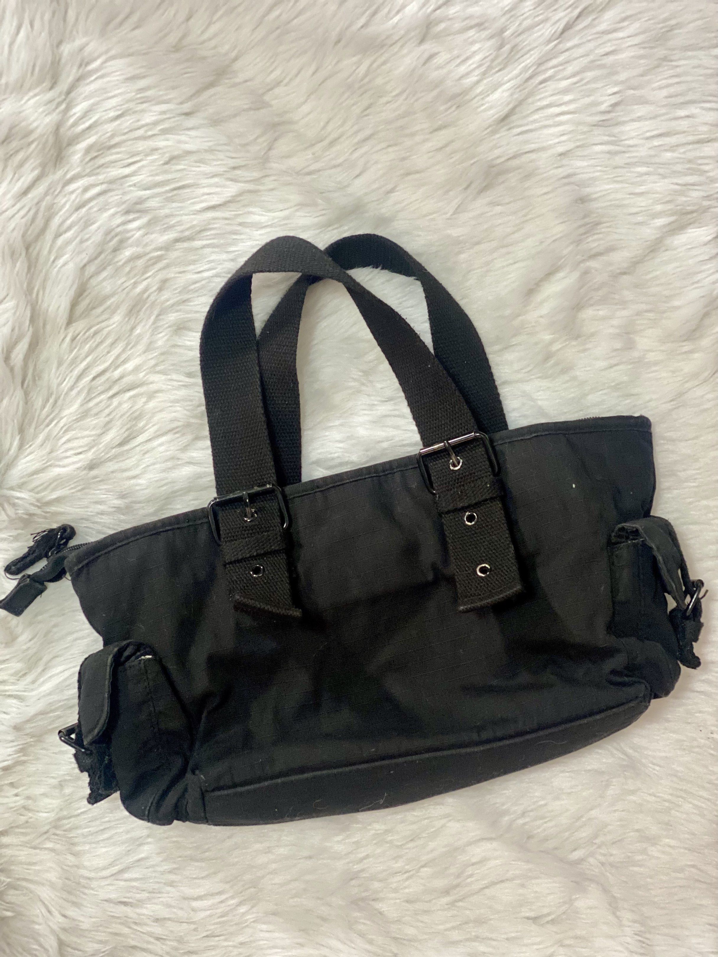 Black Canvas Handbag with Buckle Details (Category: Luxury Bags & Wallets) located in Taguig. Submitted by prelobyjen (Listing ID 1420785168, Image 3). Description: - Black canvas handbag - Tote style - Multiple pockets (2 side, 2 front) - Buckle details - Zipper closure - Two handles - Checkered interior lining - Ideal for everyday use - Taguig based.