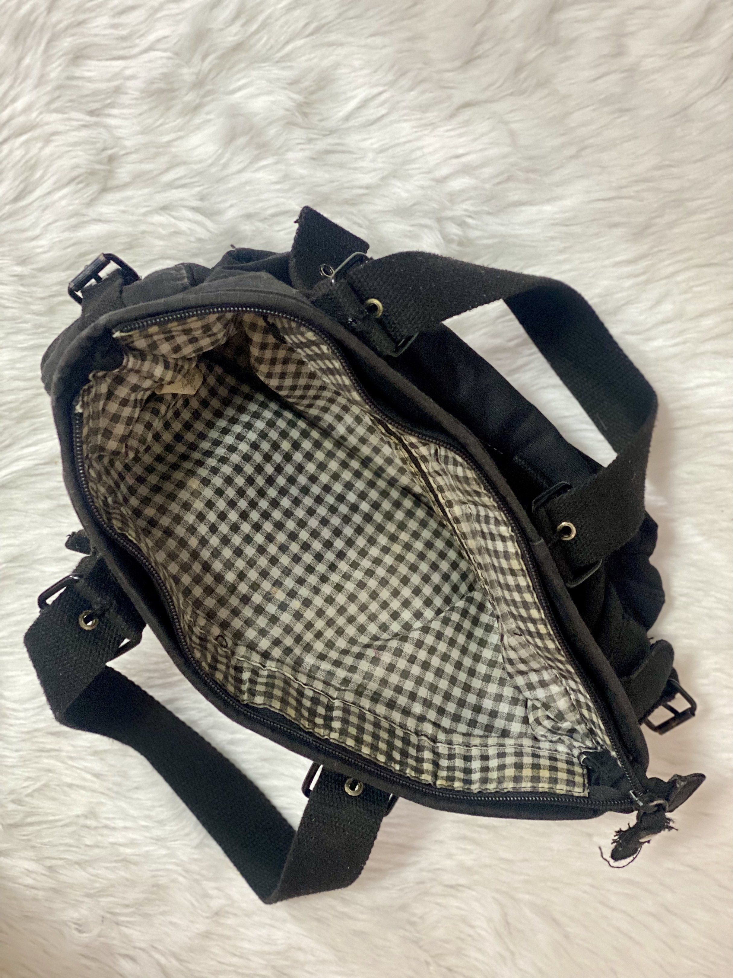 Black Canvas Handbag with Buckle Details (Category: Luxury Bags & Wallets) located in Taguig. Submitted by prelobyjen (Listing ID 1420785168, Image 2). Description: - Black canvas handbag - Tote style - Multiple pockets (2 side, 2 front) - Buckle details - Zipper closure - Two handles - Checkered interior lining - Ideal for everyday use - Taguig based.