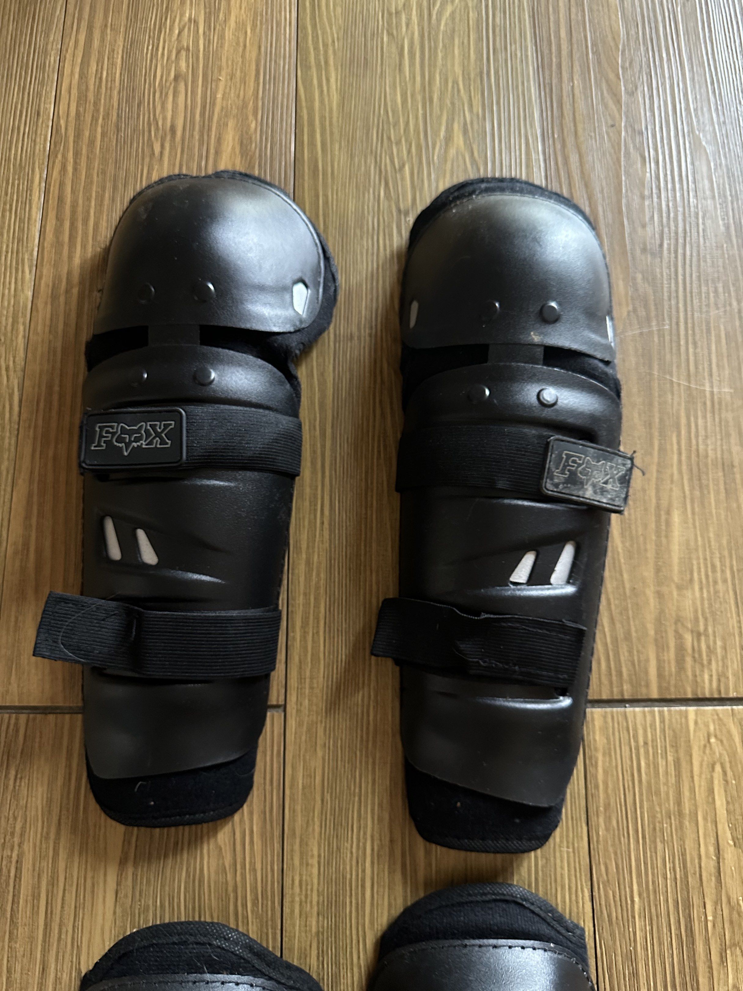 Fox Knee and Shin Guards (Category: Other Sports Equipment and Supplies) located in Caloocan City. Submitted by 2ndfash (Listing ID 1420816447, Image 3). Description: Set of Fox knee and shin guards. Features adjustable straps for a secure fit. The guards are black. The Fox logo is visible on the straps. Designed to protect knees and shins. Suitable for various activities..