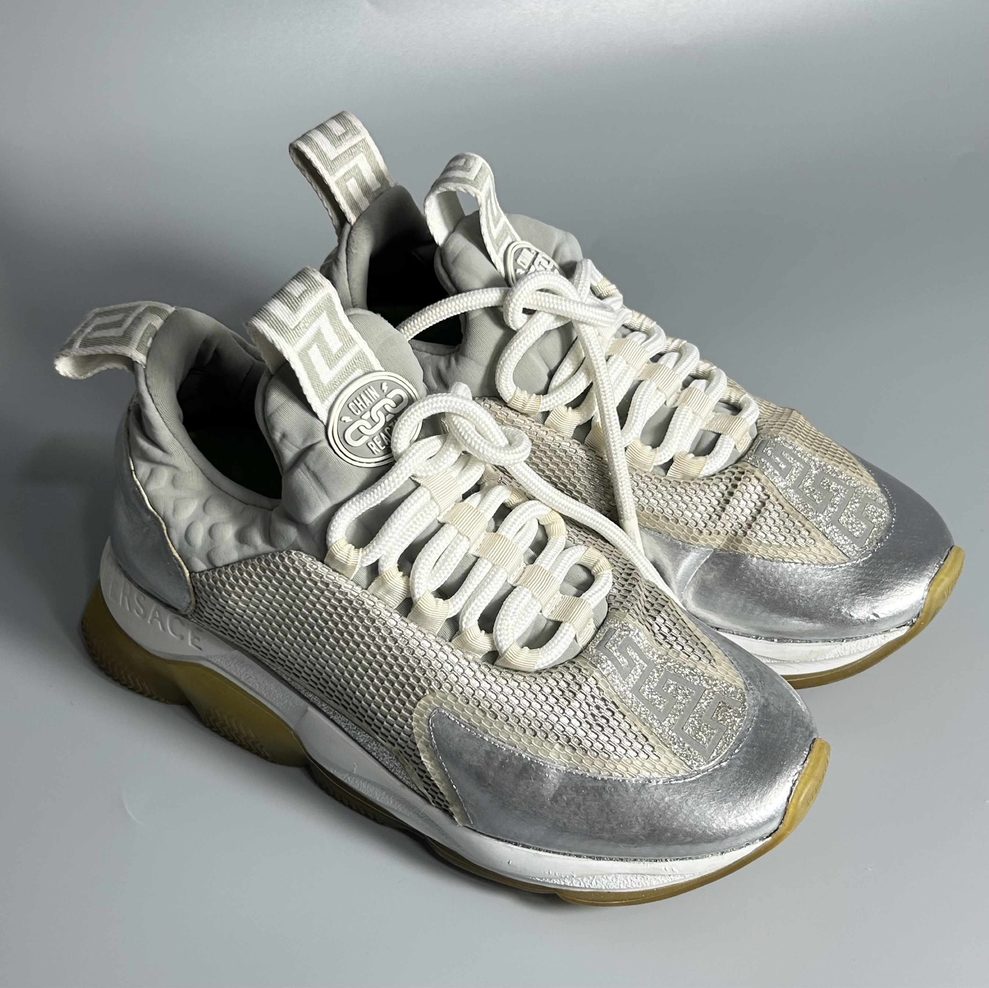 Versace Chain Reaction Sneakers (Category: Sneakers & Footwear) located in Cavite. Submitted by datsoretro (Listing ID 1420927901, Image 1). Description: - Versace Chain Reaction sneakers - Size: 37 - Color: Silver and Grey - With visible paint scratches - Features iconic Versace design - Perfect for adding a touch of luxury to your look.