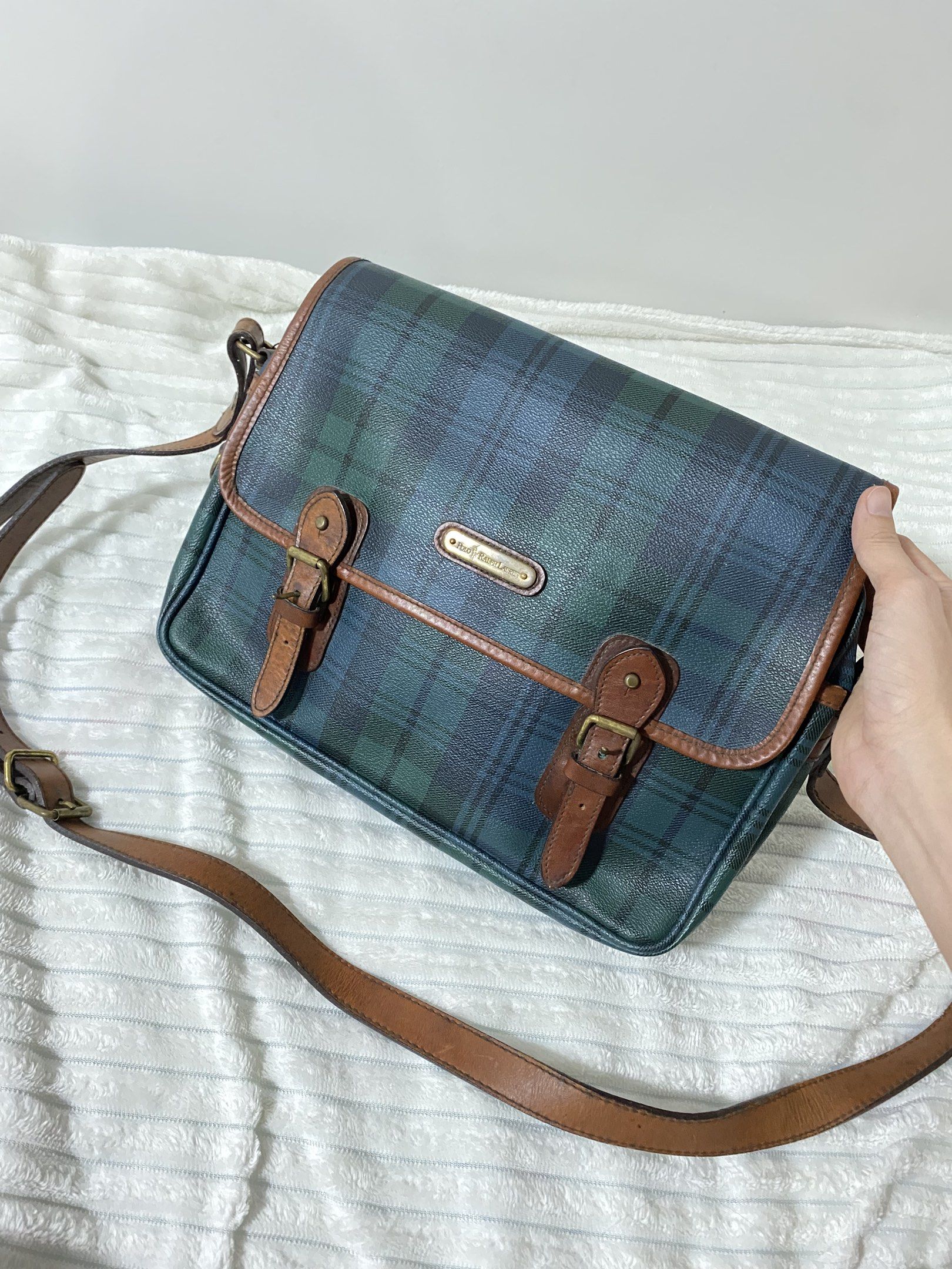 Authentic Polo Ralph Lauren Plaid Messenger Bag (Category: Luxury Bags & Wallets) located in Santa Rosa. Submitted by sassycollection. (Listing ID 1420943151, Image 1). Description: - Authentic Polo Ralph Lauren messenger bag - Green and blue plaid pattern - Brown leather trim - Adjustable shoulder strap - Flap closure with buckles - Main compartment and inner pocket - Polo Ralph Lauren logo detail.