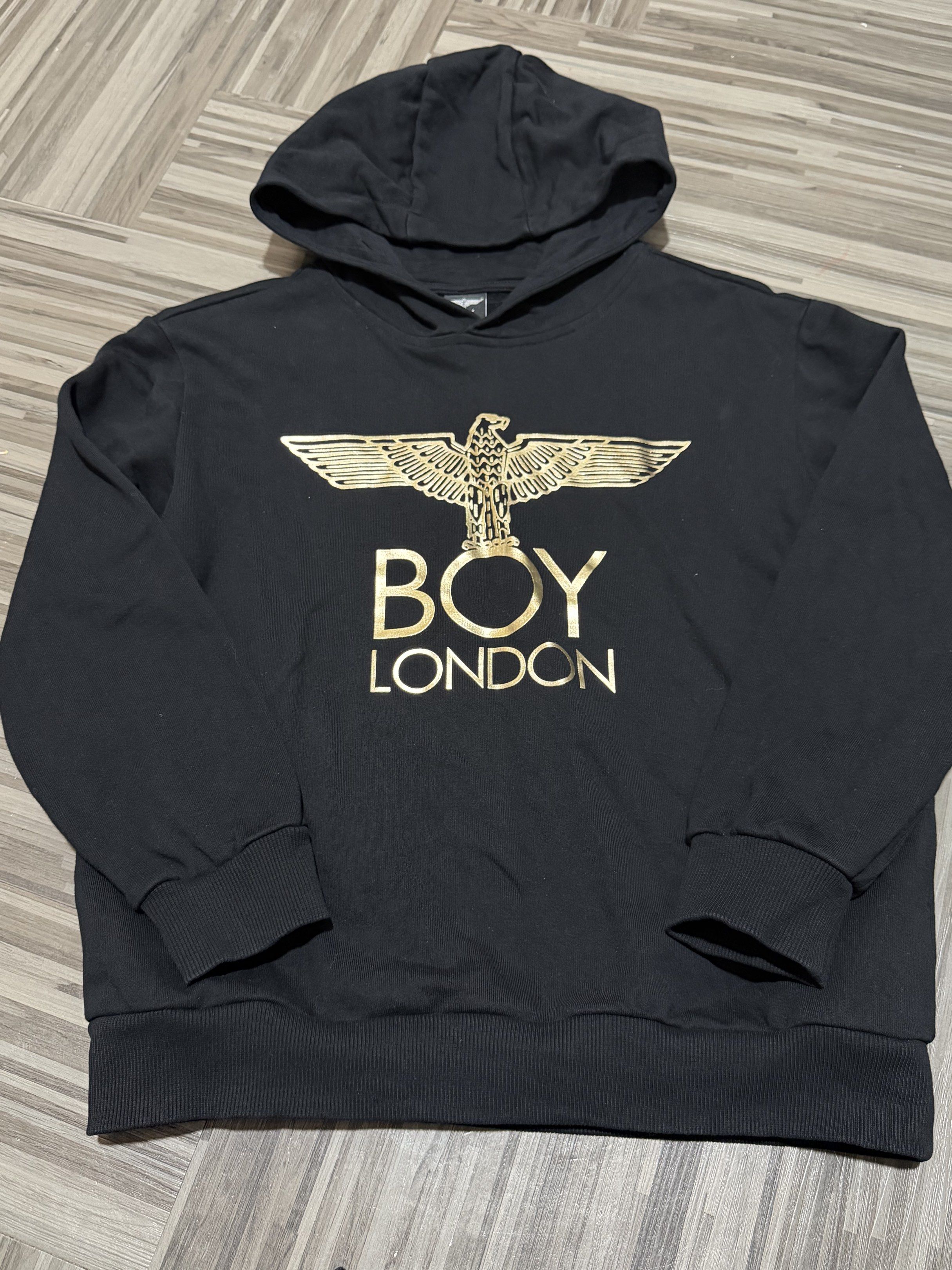 Boy London Hoodie (Category: Hoodies) located in Manila. Submitted by branded_preloved14 (Listing ID 1420987408, Image 1). Description: - Black Boy London hoodie - Features a gold eagle design - Size 150 (S-M) - Hooded with long sleeves - Suitable for casual wear -22 x 18 inches .