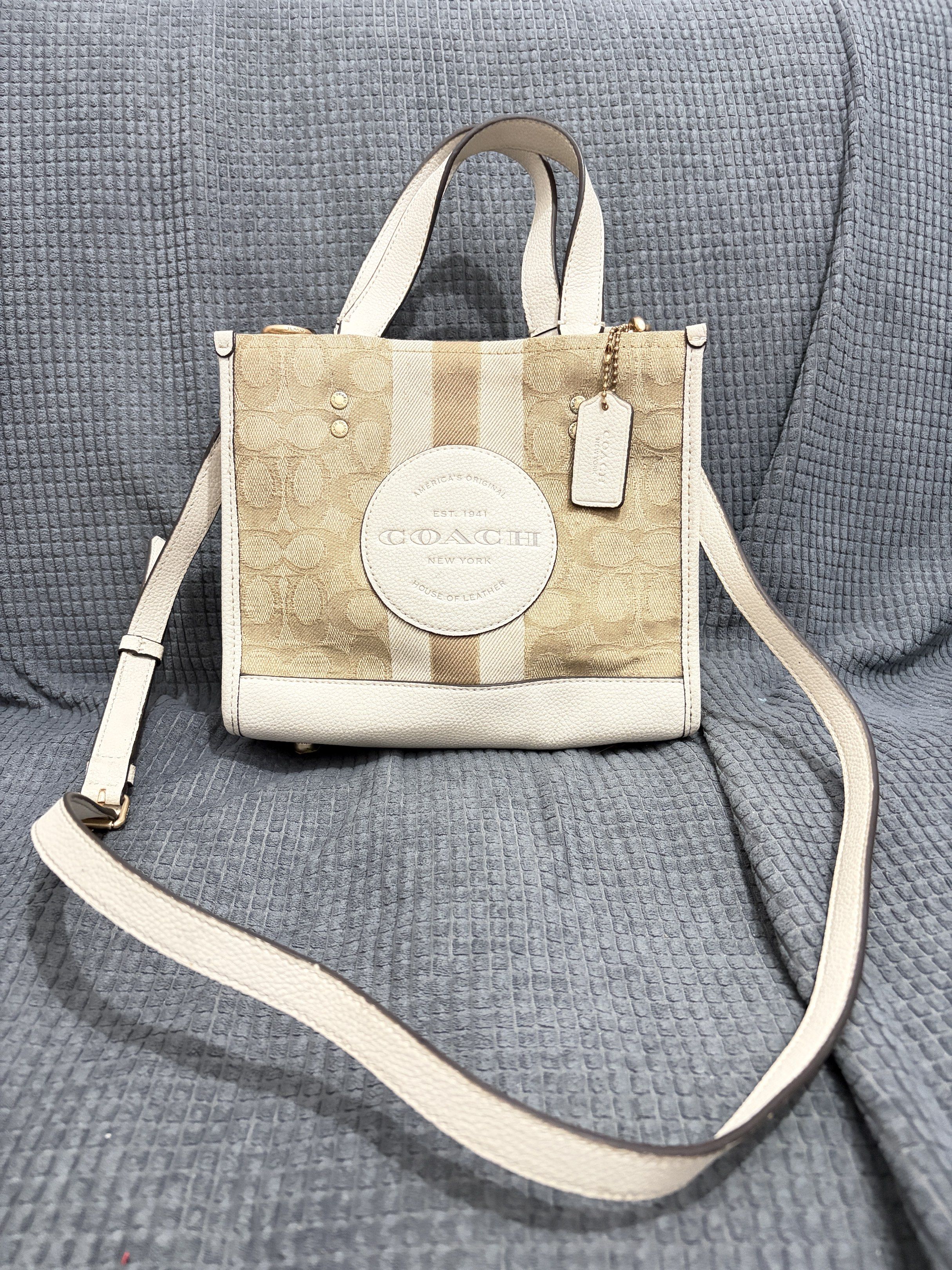 Coach Dempsey Tote 22 (Category: Luxury Bags & Wallets) located in San Juan City. Submitted by dbprelovedlux (Listing ID 1421071819, Image 1). Description: Coach Dempsey Tote with a signature coated canvas and refined white pebble leather. Features a detachable strap for shoulder or crossbody wear. Includes a Coach hangtag. The bag has a fabric lining and an interior multifunction pocket. Made in Vietnam. Flaws: minimal signs of use, minor rubber