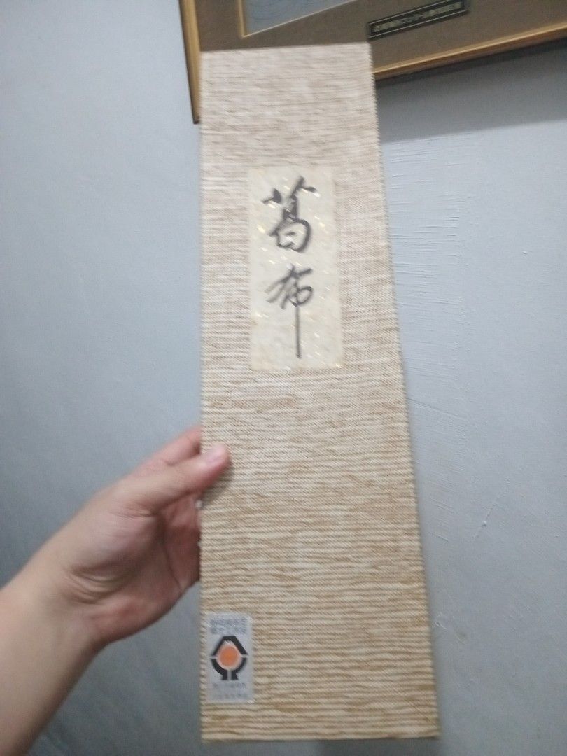 Japanese Wall Scroll (Category: Wall Decor) located in Taguig. Submitted by nippon.toki (Listing ID 1421113081, Image 1). Description: - Authentic Japanese wall scroll - Comes in original packaging (box and pamphlet) - Made of woven material - Features wooden rods - Packaging with Japanese characters and logo - Scroll is rolled up and ready to display.