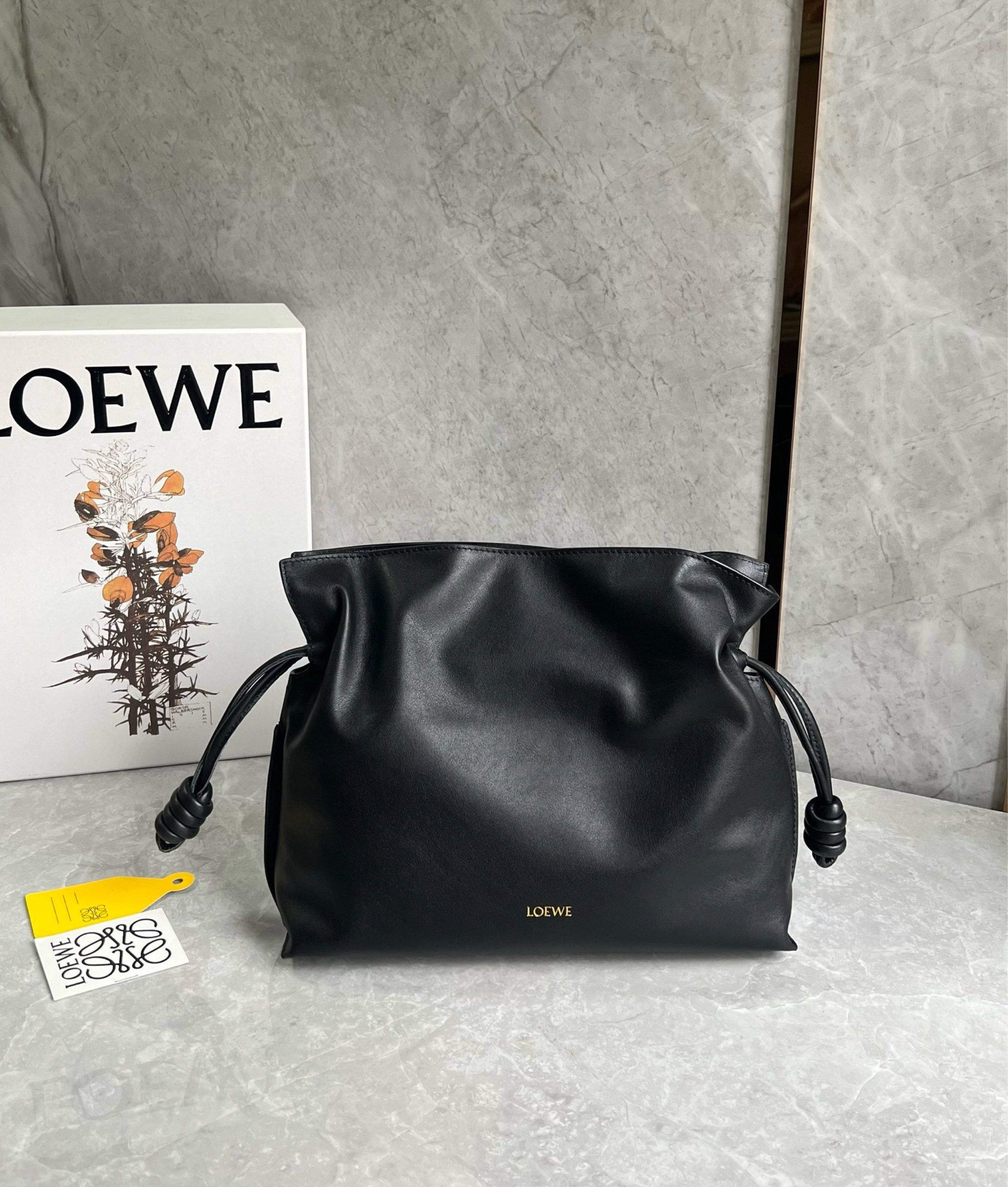 Loewe Black Leather flamenco Bag (Category: Luxury Bags & Wallets) located in Quezon City. Submitted by herluxe_official (Listing ID 1421067445, Image 2). Description: Loewe flamenco - Crafted from black leather - Stylish shoulder strap with knot details - Spacious interior with soft suede lining - Includes a small leather tag with the Loewe brand name - Comes with original Loewe box - Includes yellow tag Doesn’t have the loewe logo in the front 