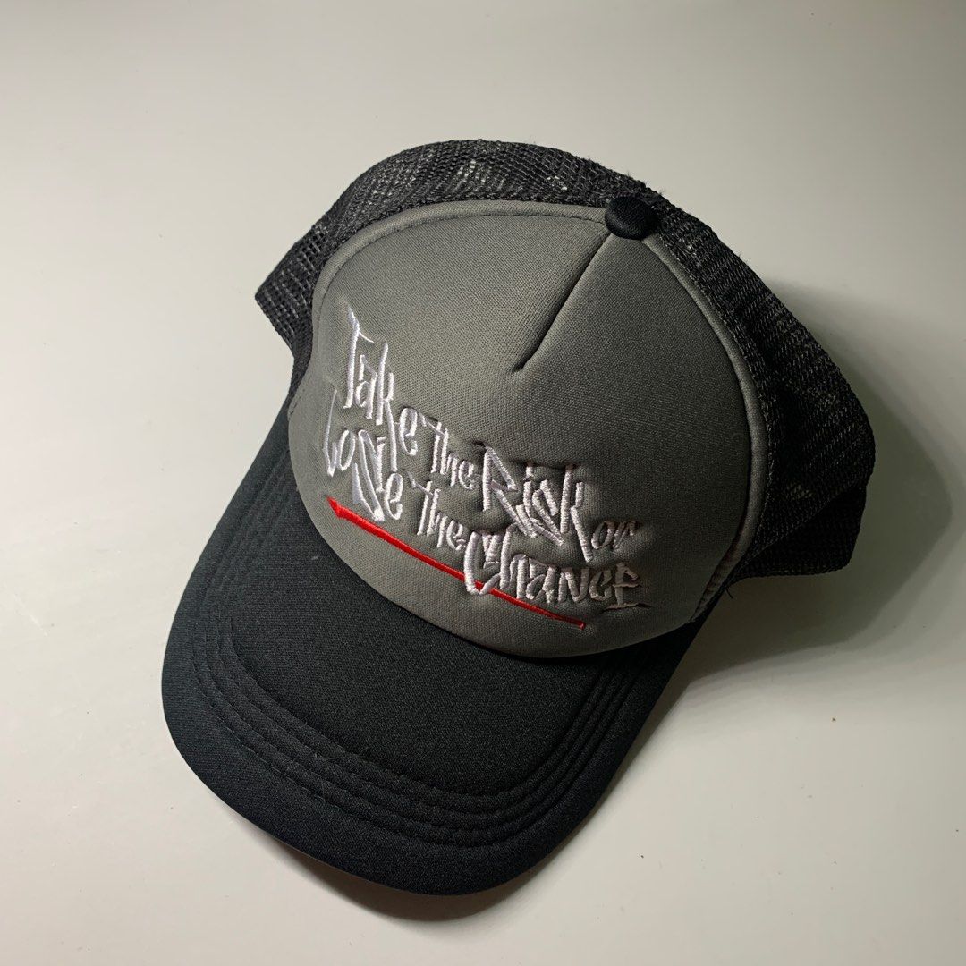 Statement Trucker Cap Take the Risk (Category: Caps & Hats) located in Pasig City. Submitted by paymelikelandlord (Listing ID 1420957432, Image 1). Description: Statement Black and gray trucker cap with embroidered text. Features a black brim, gray front panel with white and red embroidered text, and a black mesh back. The text reads "Take the Risk or Lose the Chance". The cap has an adjustable snapback closure..