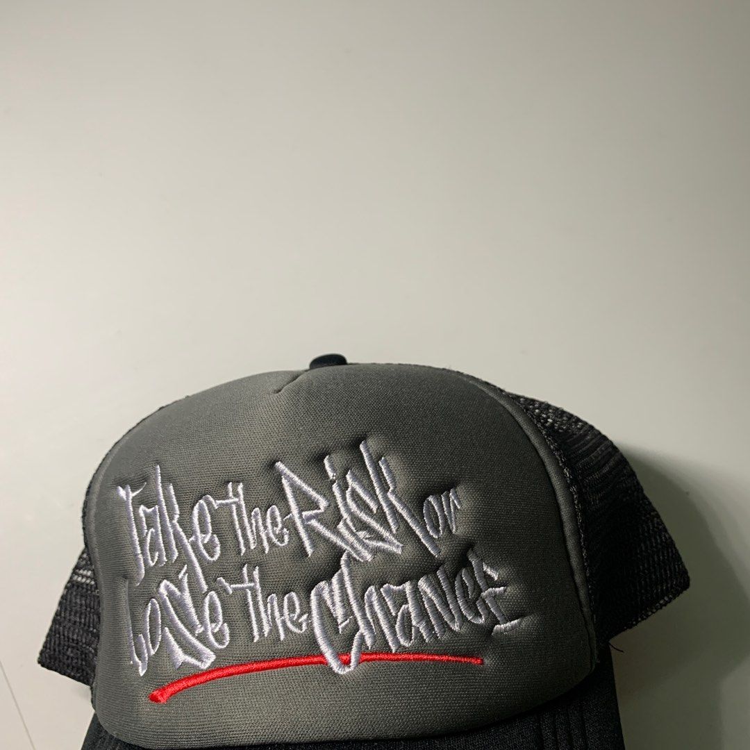 Statement Trucker Cap Take the Risk (Category: Caps & Hats) located in Pasig City. Submitted by paymelikelandlord (Listing ID 1420957432, Image 2). Description: Statement Black and gray trucker cap with embroidered text. Features a black brim, gray front panel with white and red embroidered text, and a black mesh back. The text reads "Take the Risk or Lose the Chance". The cap has an adjustable snapback closure..