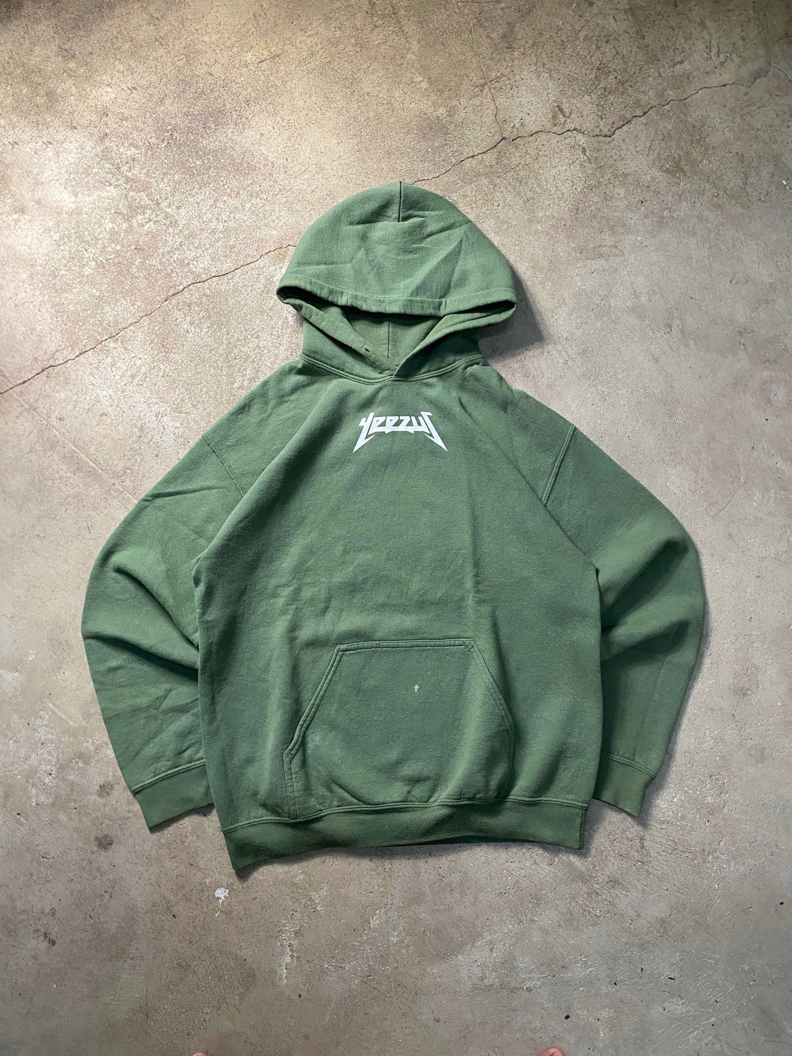 Yeezy Hoodie Olive Green (Category: Hoodies) located in Angeles City. Submitted by driptee_ph22 (Listing ID 1420938505, Image 1). Description: YEEZUS HOODIE - Width:22 - Length:28 - Olive green Yeezy hoodie - Features a "Yeezy" graphic on the back - Relaxed fit - Made of thick cotton material - Has a front pocket and hood - Minor stains on the sleeve.