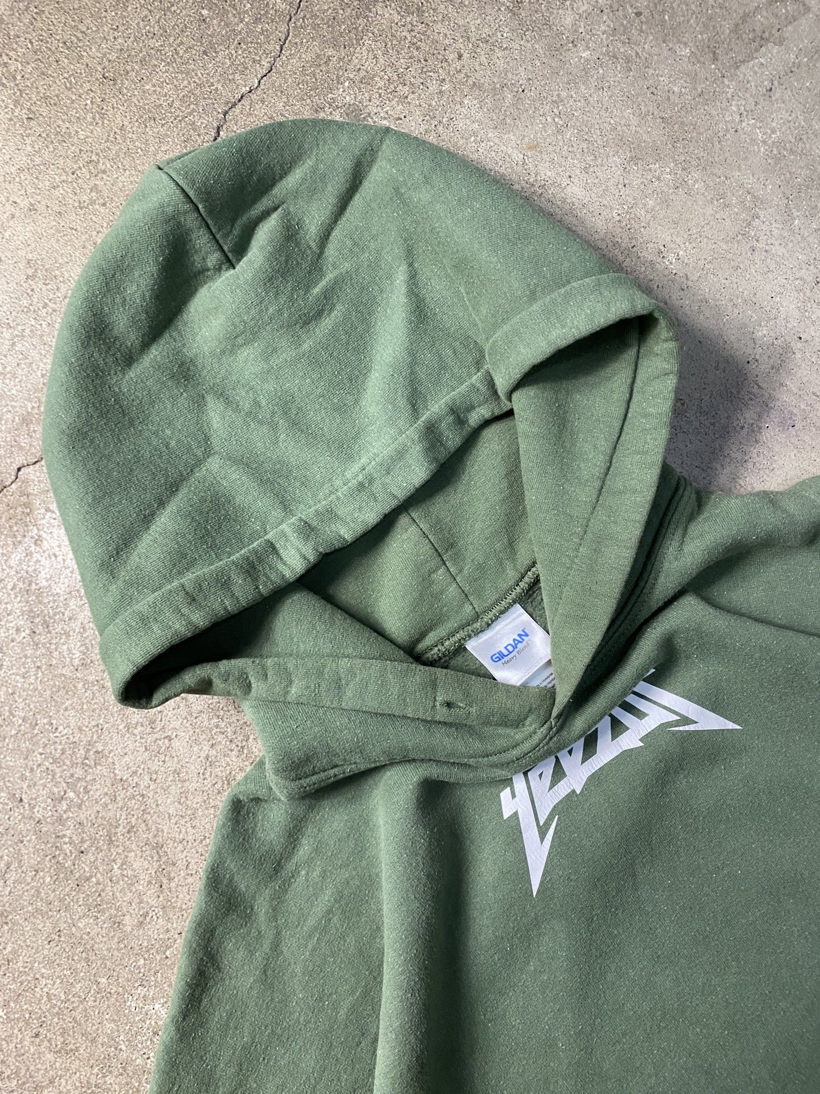 Yeezy Hoodie Olive Green (Category: Hoodies) located in Angeles City. Submitted by driptee_ph22 (Listing ID 1420938505, Image 3). Description: YEEZUS HOODIE - Width:22 - Length:28 - Olive green Yeezy hoodie - Features a "Yeezy" graphic on the back - Relaxed fit - Made of thick cotton material - Has a front pocket and hood - Minor stains on the sleeve.