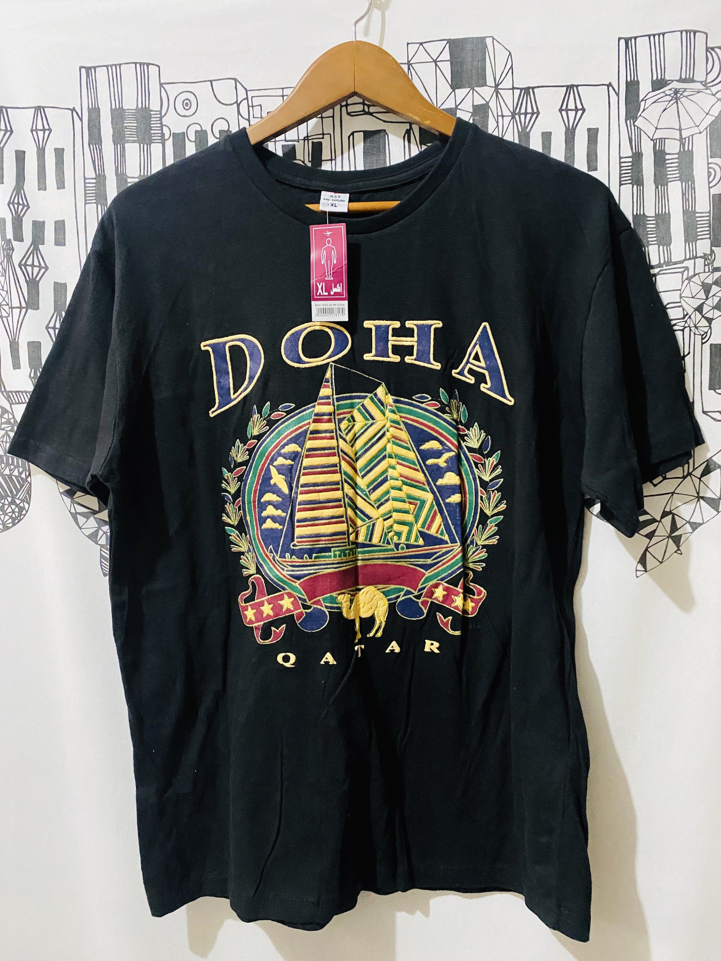 Black Doha Qatar Graphic T-shirt (Category: Tshirts & Polo Shirts ) located in Quezon City. Submitted by hirono18 (Listing ID 1421214006, Image 1). Description: - BLACK graphic t-shirt - Design includes a sailboat, camel, and stars - Crew neck style - Plain black back - Cotton soft.