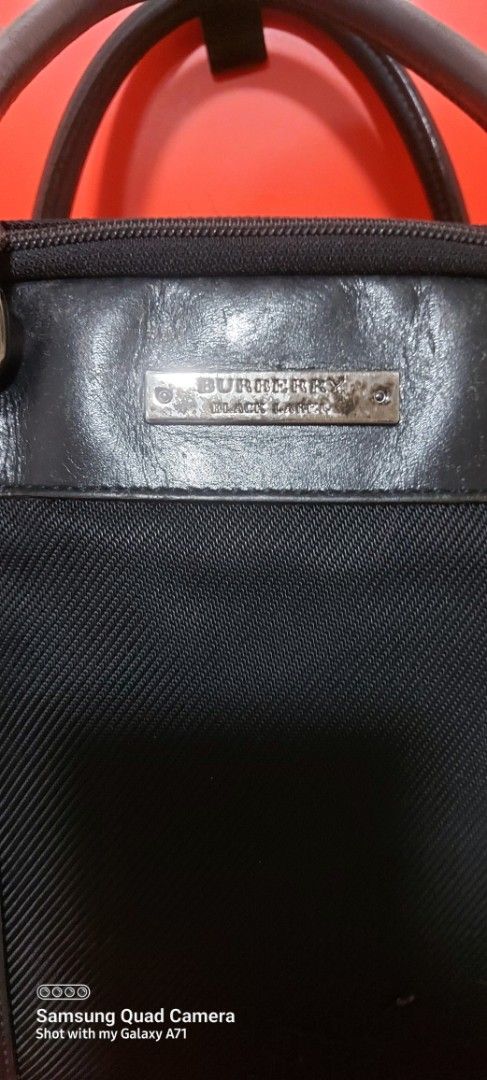 Burberry Black Label laptop/document bag (Category: Luxury Bags & Wallets) located in Quezon City. Submitted by threetwotwo2ndaccount (Listing ID 1421127450, Image 3). Description: - Burberry Black Label laptop/document bag - Black color - Top handle and detachable shoulder strap - Main compartment and interior pocket - Exterior shows wear and tear - Plaid interior lining - Zipper closure -size: H-12",L-16",W-4.5" issue: may konting scratch sa ha