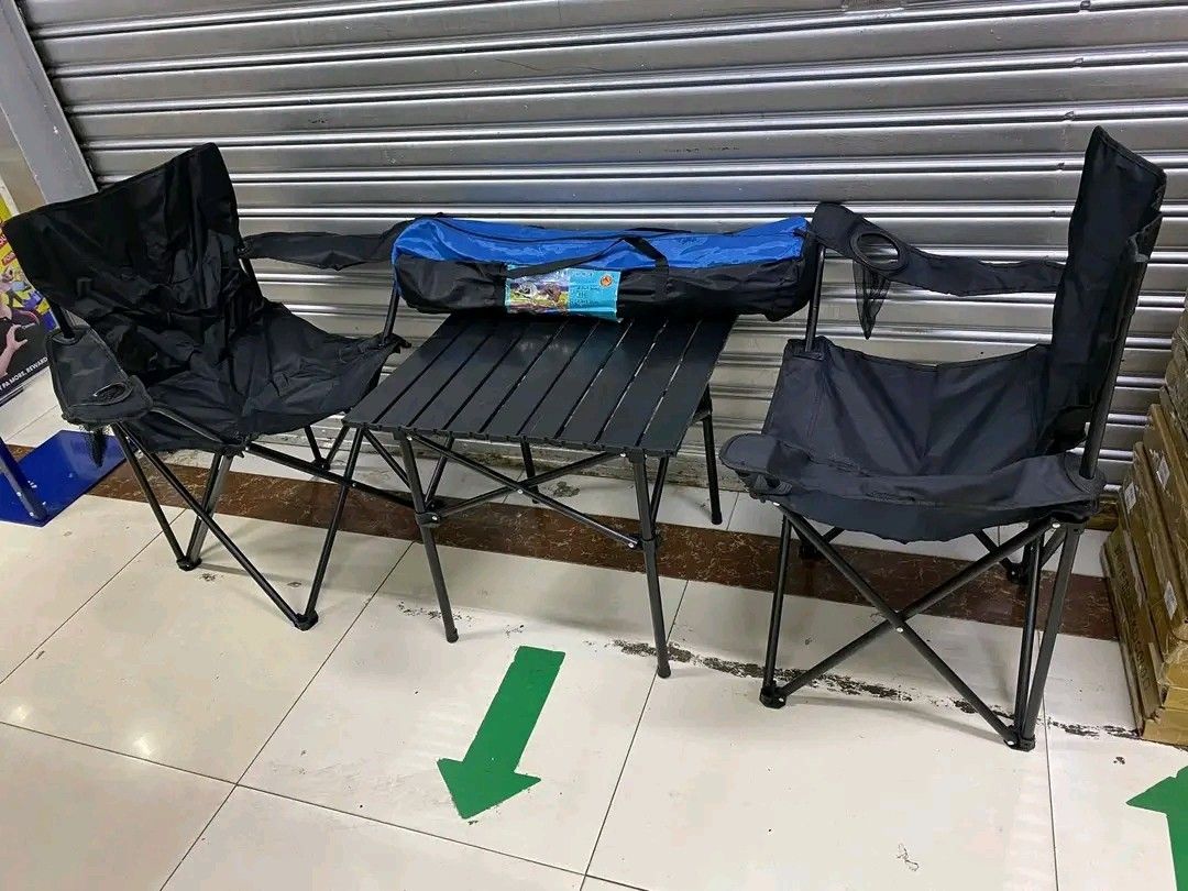 Camping Table and Chairs Set (Category: Hiking & Camping) located in Quezon City. Submitted by anghies_shop (Listing ID 1421258224, Image 1). Description: Camping set includes a folding table and two black folding chairs. The table has a slatted design. The chairs have armrests. The set comes with a carrying bag for easy transport and storage. Perfect for outdoor activities like camping, picnics, or beach trips..