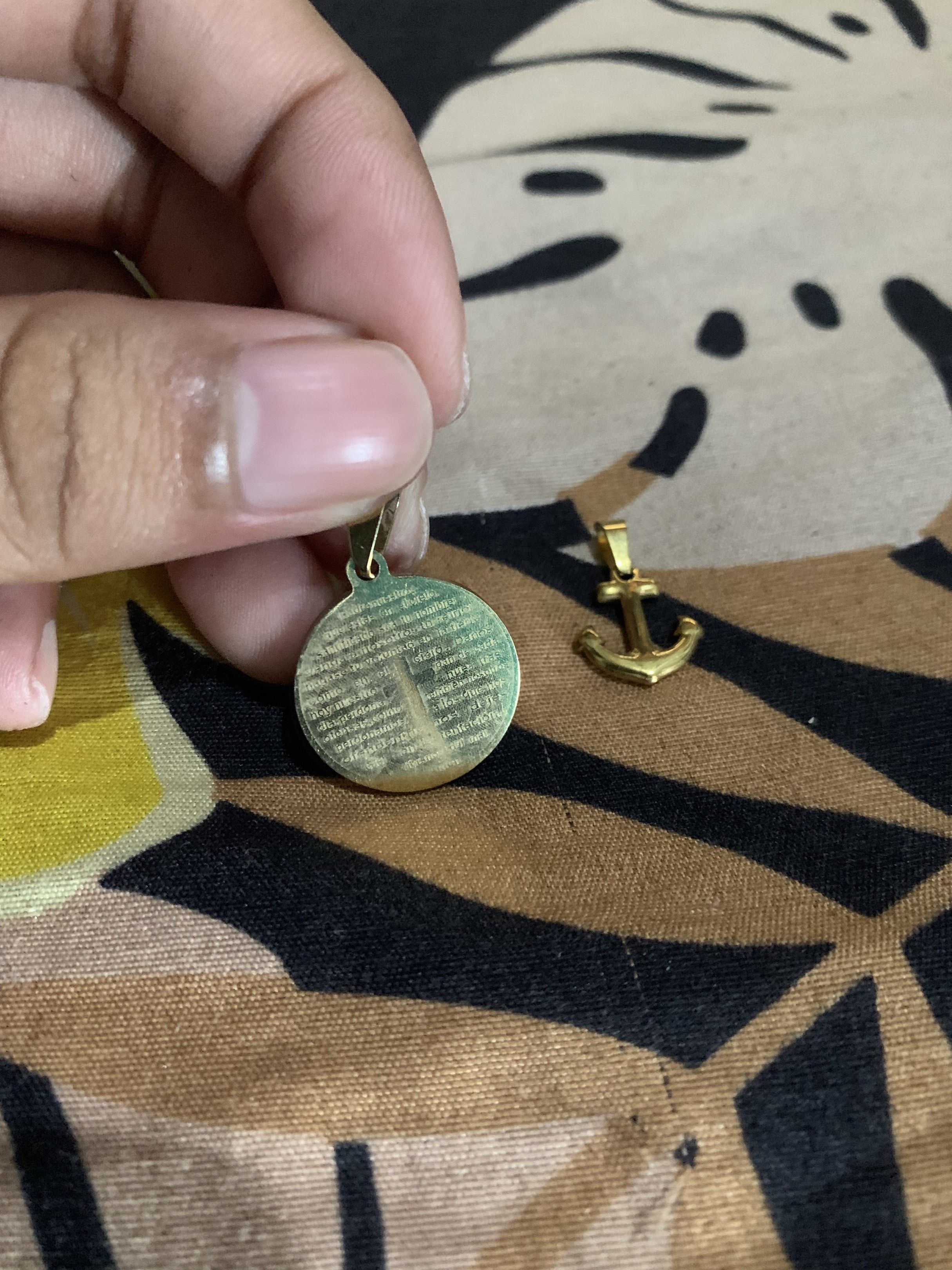 Gold-Colored Religious Pendants and anchor (Category: Charms) located in Manila. Submitted by declutteringog7 (Listing ID 1421170329, Image 1). Description: - Set of two gold-colored pendants. - Includes: - Round pendant with cross and text. - Anchor pendant. - Made of metal. - Both pendants have loops for attaching to a chain..