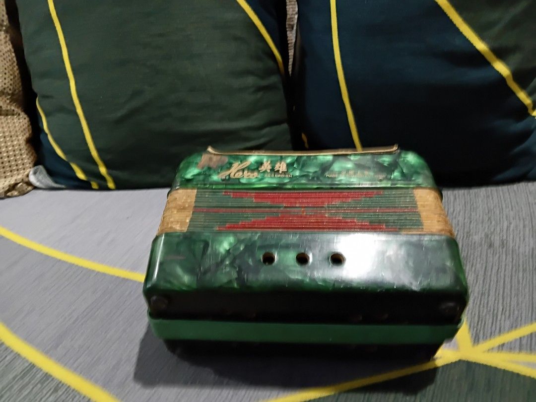 Haro Accordion - Vintage (Category: Musical Instruments) located in Rizal. Submitted by geniustito65 (Listing ID 1421208425, Image 2). Description: Vintage Haro accordion in green and gold. Features a keyboard with white keys and a gold mesh front. The accordion has a unique design with visible wear and tear, adding to its vintage charm. The bellows appear intact. The accordion has a red and gold design on the front..