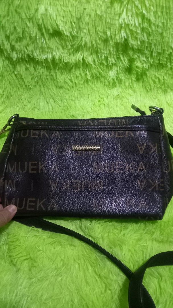 MUEKA Crossbody Bag (Category: Cross-body Bags) located in Manila. Submitted by twinklelyn03 (Listing ID 1421291794, Image 1). Description: - Black MUEKA crossbody bag - Adjustable long strap - Multiple zippered compartments for organization - Light grey interior lining - Gold-colored accent - Made of a leather-like material.