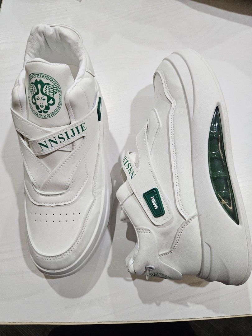 NNSIJIE White Sneakers (Category: Sneakers) located in Manila. Submitted by honeypatch (Listing ID 1421223957, Image 2). Description: - White sneakers with a unique design - Features a strap with "NNSIJIE" branding - Visible air cushion sole - Green accent on the strap - Versace like logo on the tongue - Thick sole for added comfort and style - RFS: Originally bought for Monito Monita but recipient went AWOL so Im selling it instead. - Brand New 