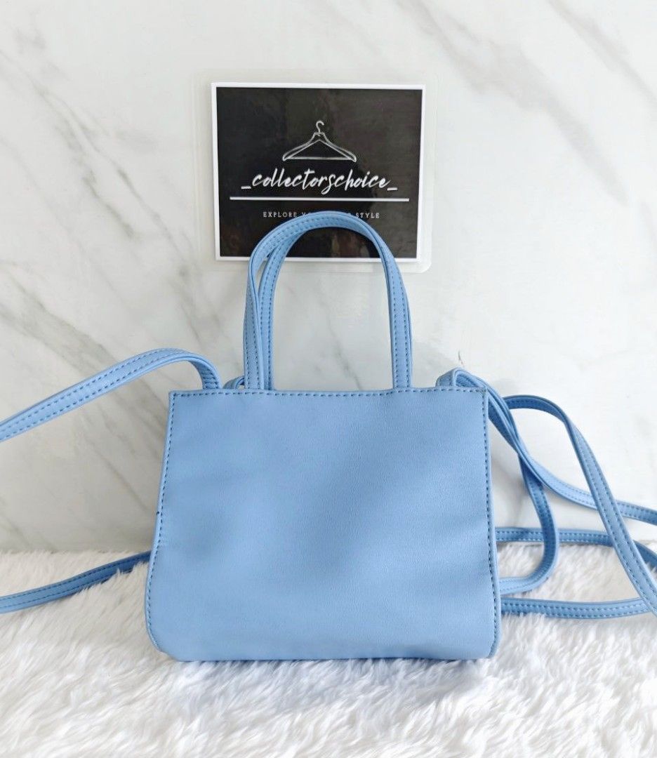 Telfar Small Cerulean Shopping Bag (Category: Luxury Bags & Wallets) located in Makati City. Submitted by _collectorschoice_ (Listing ID 1421271681, Image 3). Description: ° This mini tote is constructed of faux leather in cerulean with the iconic raised Telfar logo at the front ° The shoulder bag has thin blue handles and a long crossbody strap ° The bag opens to a blue fabric interior ° Blue vegan leather ° Silver-tone hardware ° Flat handles &