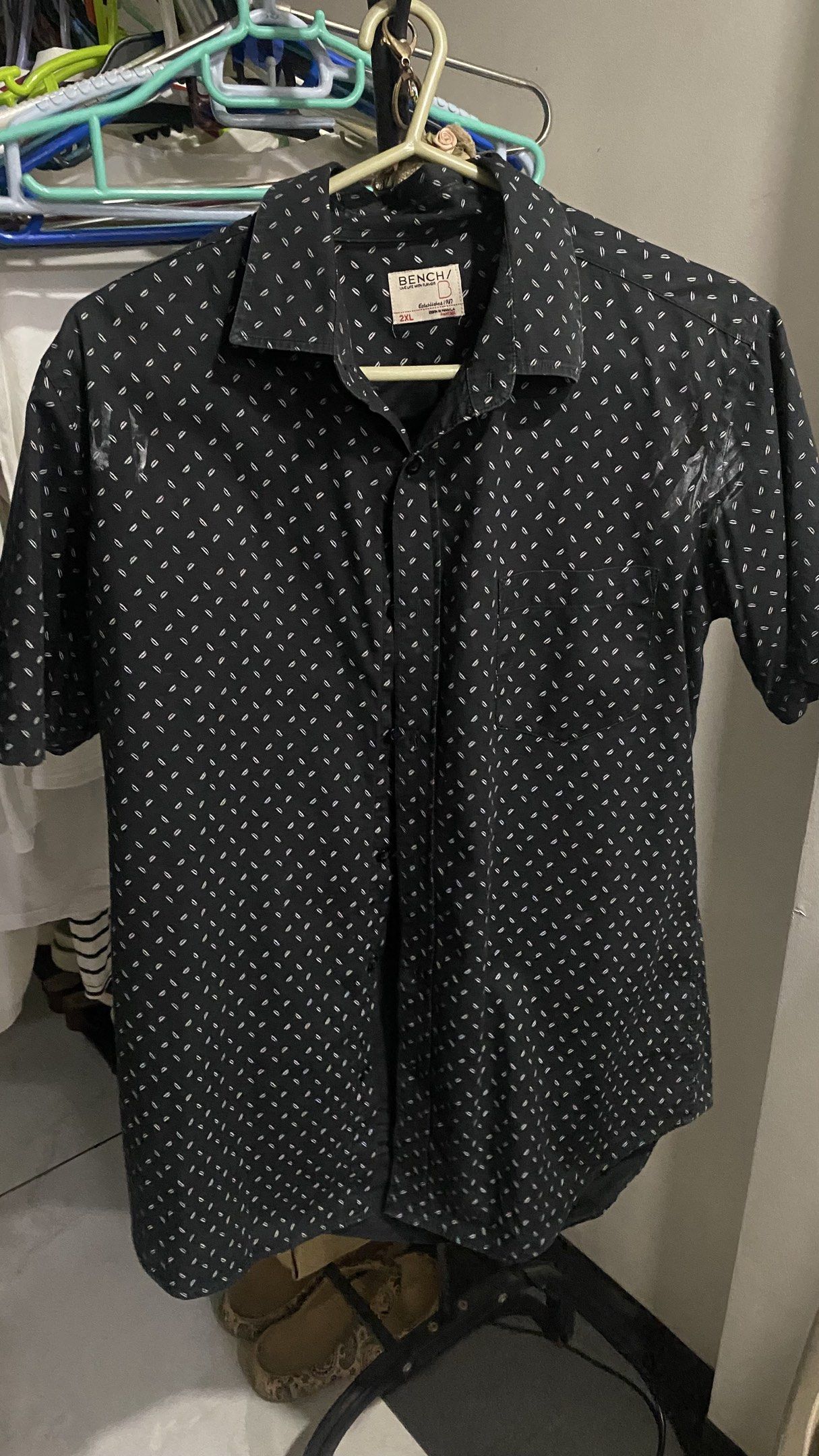 Bench Black Printed Shirt - 2XL (Category: Tshirts & Polo Shirts ) located in Malabon City. Submitted by kridcollections (Listing ID 1421403454, Image 1). Description: - Bench black short-sleeved shirt - Size: 2XL (fits Large) - Features a subtle white pattern - Button-down front - Classic collar - Comfortable fabric - Ideal for casual wear.