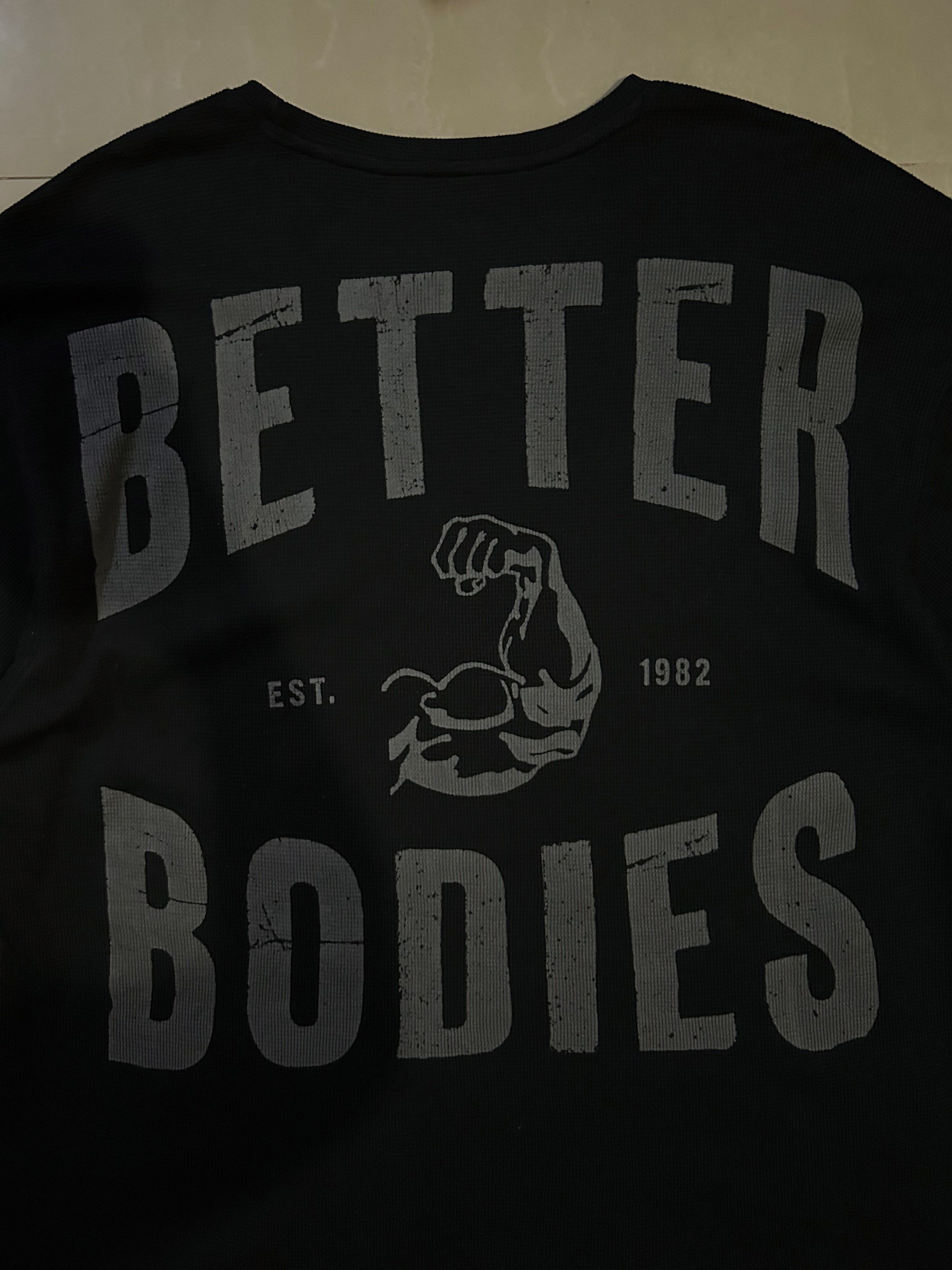 Better Bodies Black Waffle T-shirt (Category: Tshirts & Polo Shirts ) located in San Fernando. Submitted by thrift_lang_ni_kim (Listing ID 1421307010, Image 2). Description: - Better Bodies Waffle T-shirt - Black color - Size: M - Width 25 - Length 31 - Crew neck - Graphic print on the back: "BETTER BODIES" with muscle arm - Smaller graphic on the front - Textured fabric.