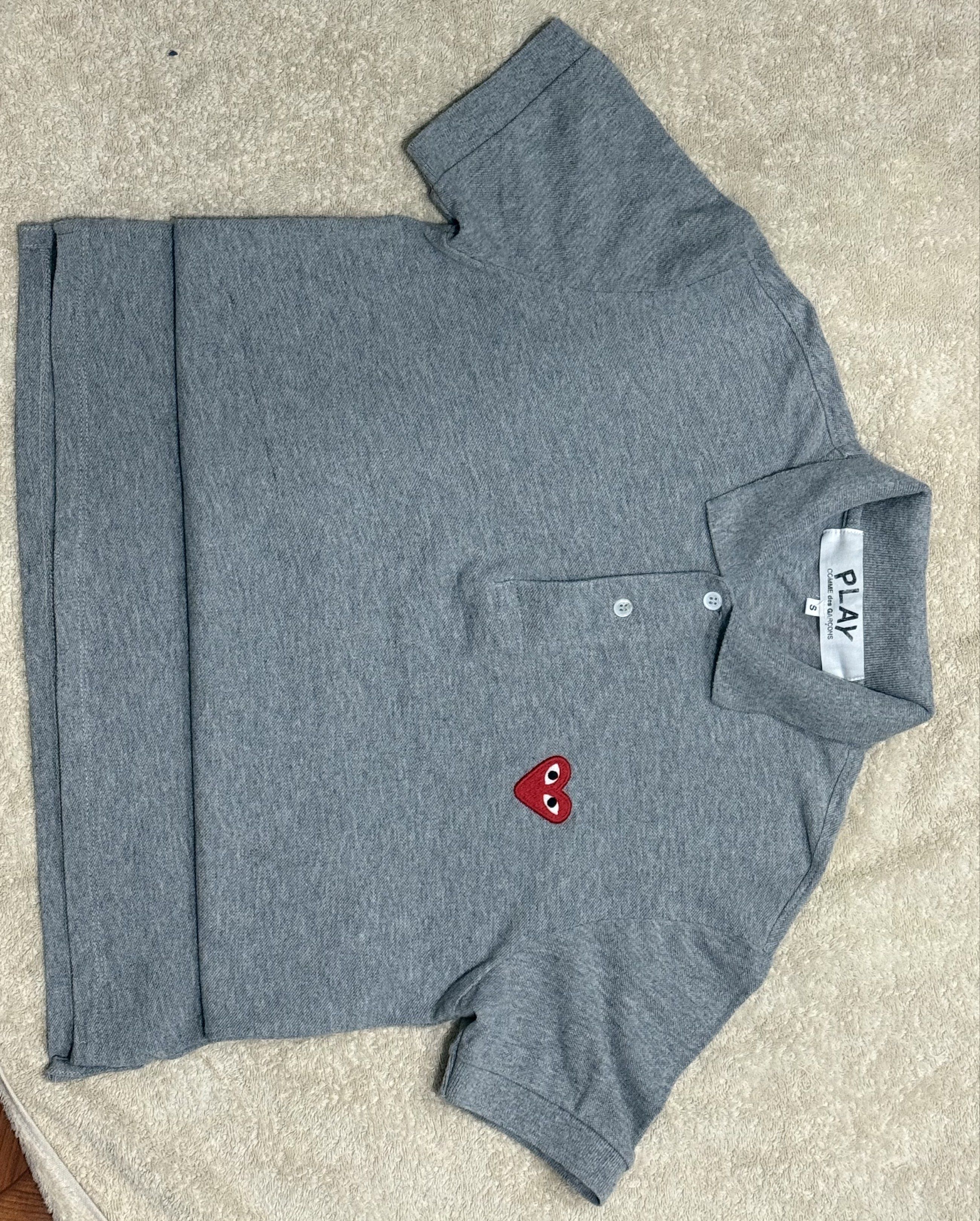 Comme des Garcons Play Polo Shirt (Category: Tshirts & Polo Shirts ) located in Manila. Submitted by jpadapat21 (Listing ID 1421403214, Image 3). Description: Authentic - Comme des Garcons Play polo shirt - Gray color - Features the iconic heart logo - Collared neckline - Button closure - Short sleeves - Classic fit - Size tag visible - 18x26.
