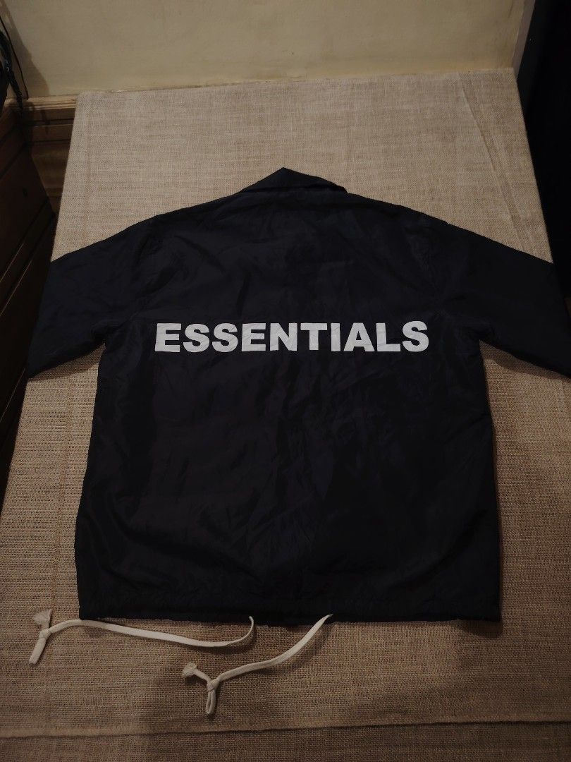 Essentials Coach Jacket Black (Category: Coats, Jackets and Outerwear) located in San Jose. Submitted by mickogapas67563 (Listing ID 1421332729, Image 2). Description: - Essentials black coach jacket - Size: Large - Features: - Button-up front - Collar - Drawstring hem - Back print: 'ESSENTIALS' in white - Material: 60% cotton - Lining: Gray.