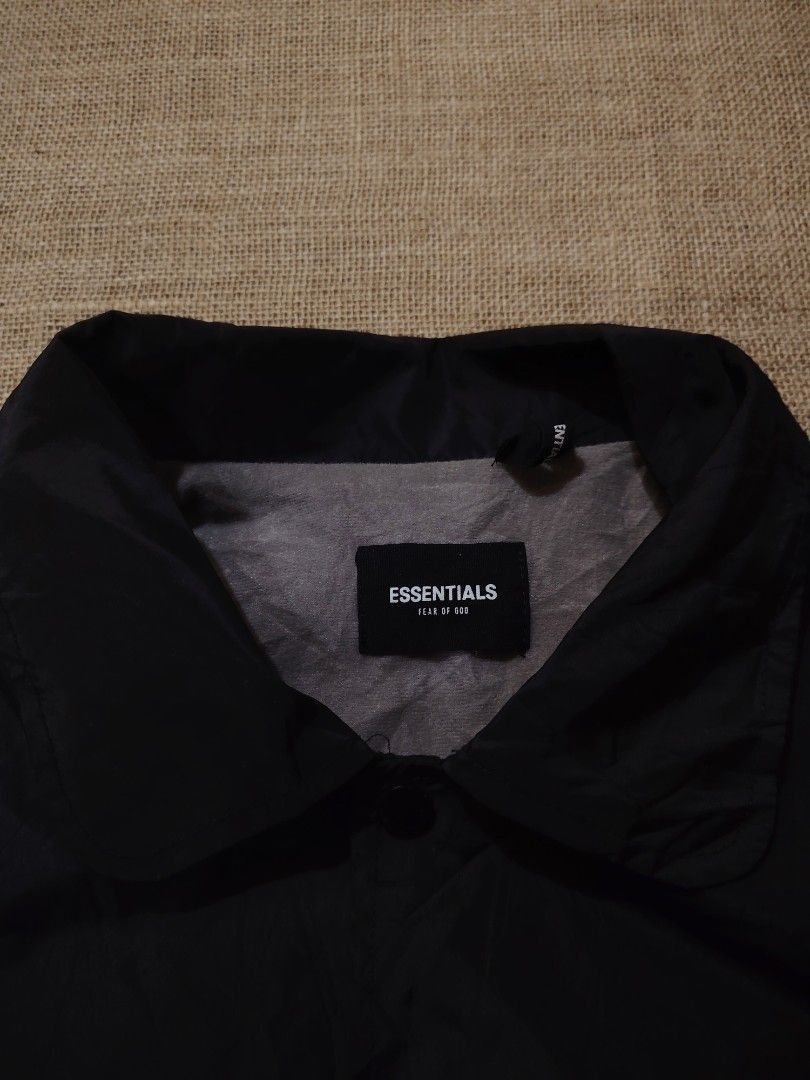 Essentials Coach Jacket Black (Category: Coats, Jackets and Outerwear) located in San Jose. Submitted by mickogapas67563 (Listing ID 1421332729, Image 3). Description: - Essentials black coach jacket - Size: Large - Features: - Button-up front - Collar - Drawstring hem - Back print: 'ESSENTIALS' in white - Material: 60% cotton - Lining: Gray.