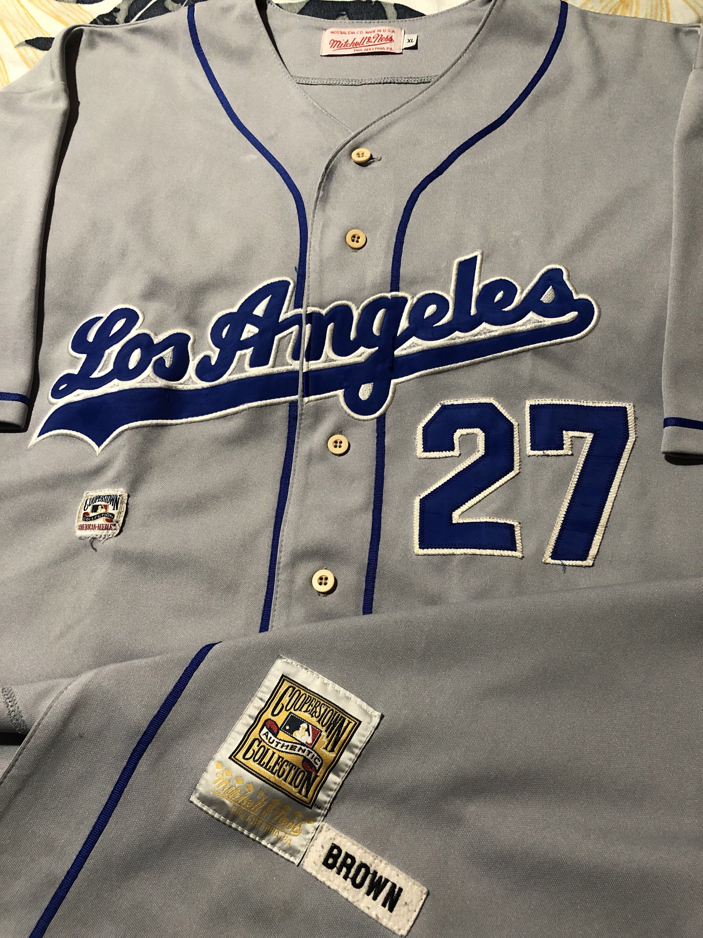 Mitchell & Ness Los Angeles Dodgers Jersey (Category: Activewear) located in Manila. Submitted by bakithrift213 (Listing ID 1421343064, Image 3). Description: - Authentic Mitchell & Ness Los Angeles Dodgers baseball jersey - Features "Los Angeles" across the chest and number "27" on front and back - Color: Grey with blue accents and trim - Button-up front - Includes a "Brown" patch - Size: XL.