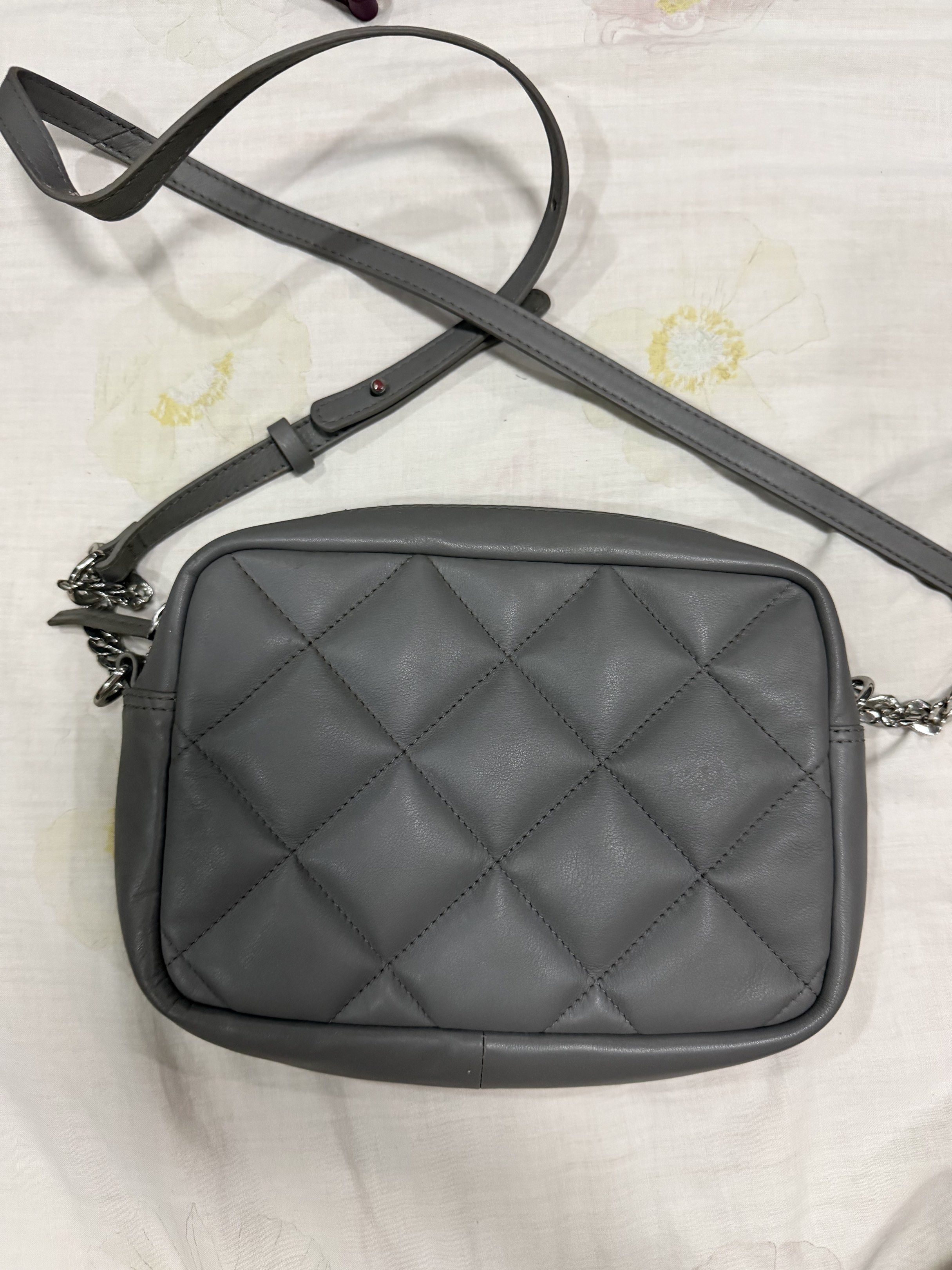 M&S Collection Quilted Crossbody Bag (Category: Cross-body Bags) located in Quezon City. Submitted by chasy9 (Listing ID 1421420018, Image 1). Description: - Gray crossbody bag from M&S Collection - Features a quilted design on the front and a chain detail on the sides - The bag has a zippered main compartment and an interior pocket - Includes an adjustable strap. Slight wear on the straps as shown in photo - Leather is still in very good conditi