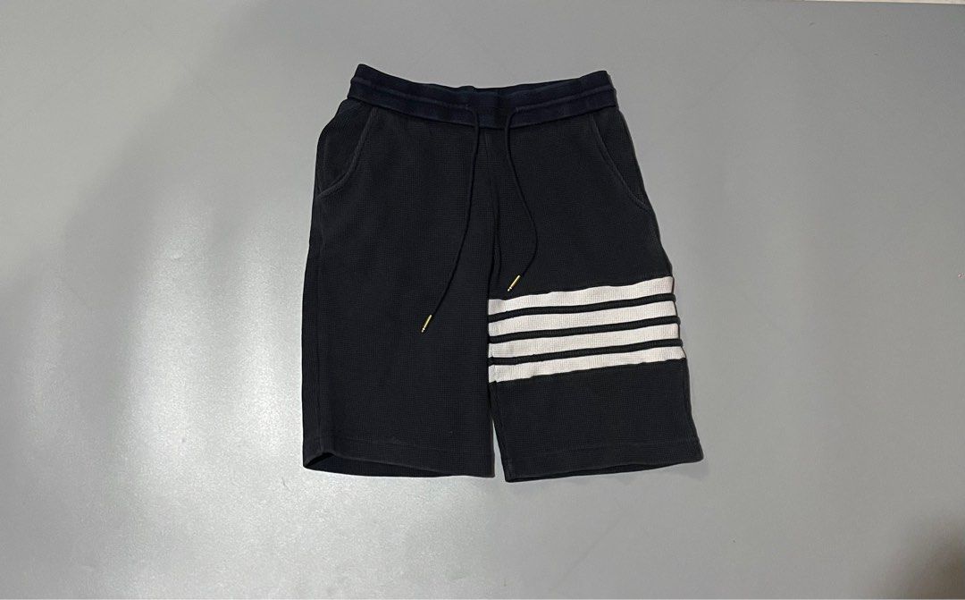 Thom Browne Waffle Knit Shorts (Category: Luxury Apparel) located in Angeles City. Submitted by andreiboughts (Listing ID 1421294889, Image 1). Description: Length: 21 Waist: 26-34 MAX (Garterized) - Authentic Thom Browne shorts - Made in Japan - Black waffle knit fabric - Signature white stripes on the side - Drawstring waist with gold-toned hardware - Thom Browne label visible - Size 1 - Navy blue waistband with red and white stripes.