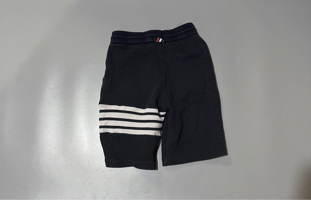 Thom Browne Waffle Knit Shorts (Category: Luxury Apparel) located in Angeles City. Submitted by andreiboughts (Listing ID 1421294889, Image 2). Description: Length: 21 Waist: 26-34 MAX (Garterized) - Authentic Thom Browne shorts - Made in Japan - Black waffle knit fabric - Signature white stripes on the side - Drawstring waist with gold-toned hardware - Thom Browne label visible - Size 1 - Navy blue waistband with red and white stripes.