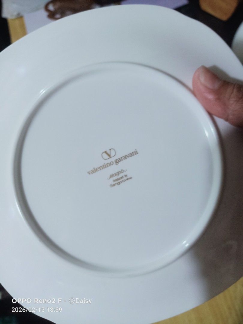 Valentino Garavani Angelo Plates(5pcs) (Category: Dinnerware & Cutlery) located in Quezon City. Submitted by uydaisy1979 (Listing ID 1421387484, Image 3). Description: Set of Valentino Garavani Angelo plates. Features a white base with a gold rim and a repeating gold floral pattern. The plates have a unique, slightly irregular shape. The Valentino Garavani logo is visible on the underside of the plates, along with the Angelo collection name and t