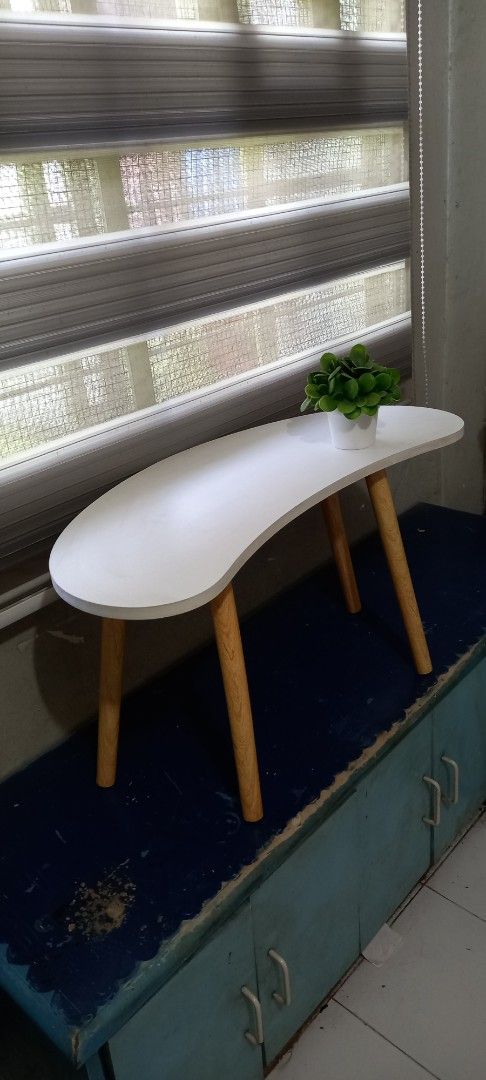 White Coffee Table with Wooden Legs (Category: Tables & Sets) located in Taytay. Submitted by decluttering_is_fun_by_dr_a (Listing ID 1421300475, Image 2). Description: - Stylish white coffee table - Unique curved design - Sturdy wooden legs - Perfect for small spaces - Ideal for drinks, books, and plants - Adds a decorative touch to any room H-42, L -76, w-30 po.
