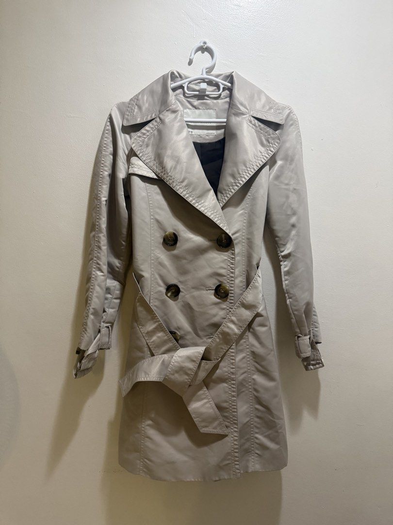Beige Double-Breasted Trench Coat (Category: Coats, Jackets and Outerwear) located in Makati City. Submitted by nemkd (Listing ID 1421571073, Image 1). Description: - Beige double-breasted trench coat - Includes a matching belt - Features button details and sleeve straps - Creates a flattering silhouette - A classic wardrobe piece.