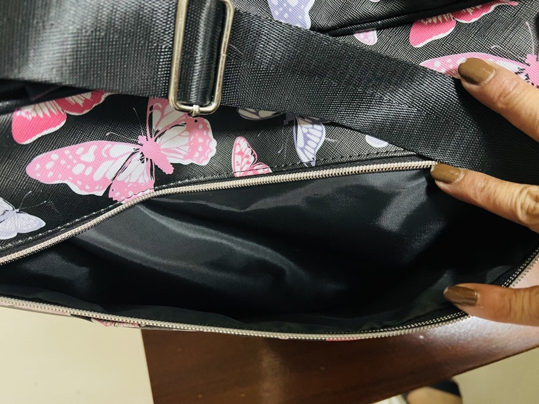 Butterfly Print Duffle Bag (Category: Luxury Bags & Wallets) located in Antipolo. Submitted by murapod2 (Listing ID 1421617007, Image 3). Description: Duffle bag features a vibrant butterfly print on a black background. It has a top handle and a detachable shoulder strap for versatile carrying options. The bag includes a main compartment and a side pocket, both with zipper closures. The interior is lined with black fabric. Came from Hawaii .