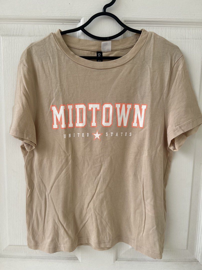 H&M Divided Midtown T-shirt (Category: Shirts) located in Quezon City. Submitted by millevlrd_ (Listing ID 1421509859, Image 1). Description: - H&M Divided T-shirt - Color: Tan - Size: S - Design: 'MIDTOWN' graphic with 'UNITED STATES' and star - Features: Crew neck, short sleeves.