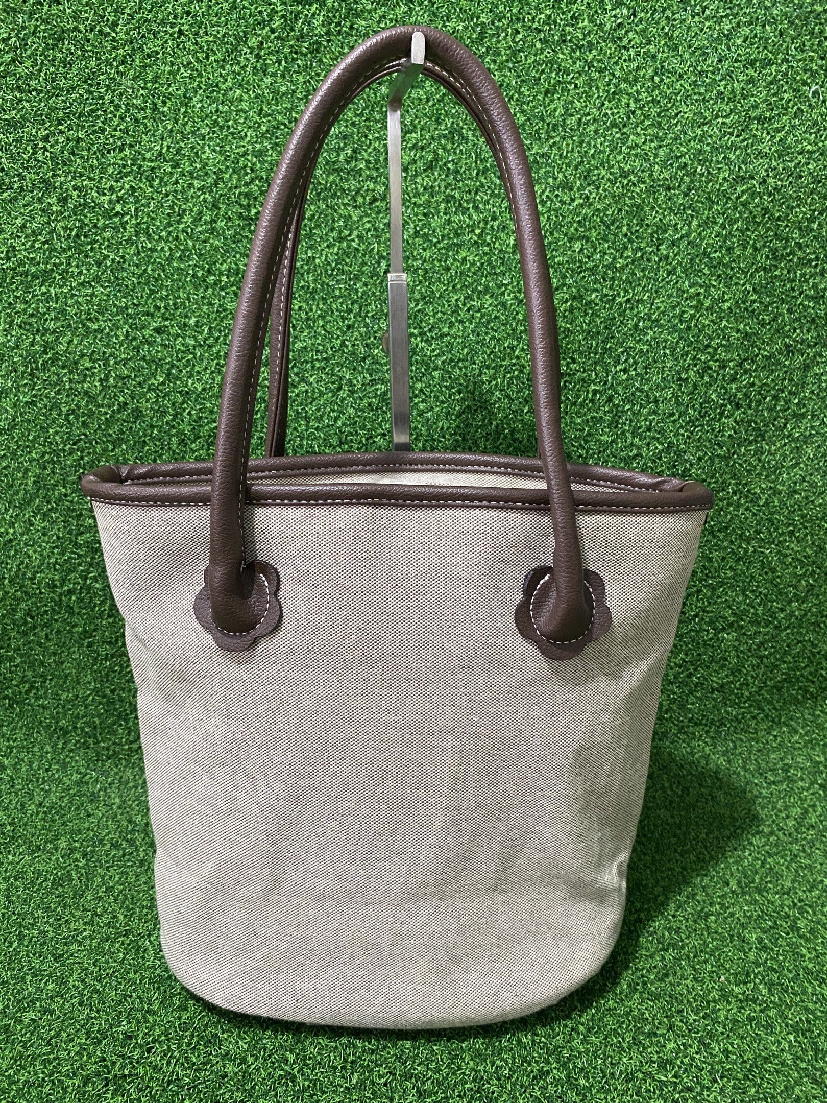Kitamura Tote Bag (Category: Tote Bags) located in Naga. Submitted by taurusg (Listing ID 1421559546, Image 2). Description: - Kitamura tote bag - Light-colored exterior - Brown leather handles and trim - Pink fabric interior - Interior zippered pocket - Top zipper closure - Small logo on front - Oval-shaped bottom.