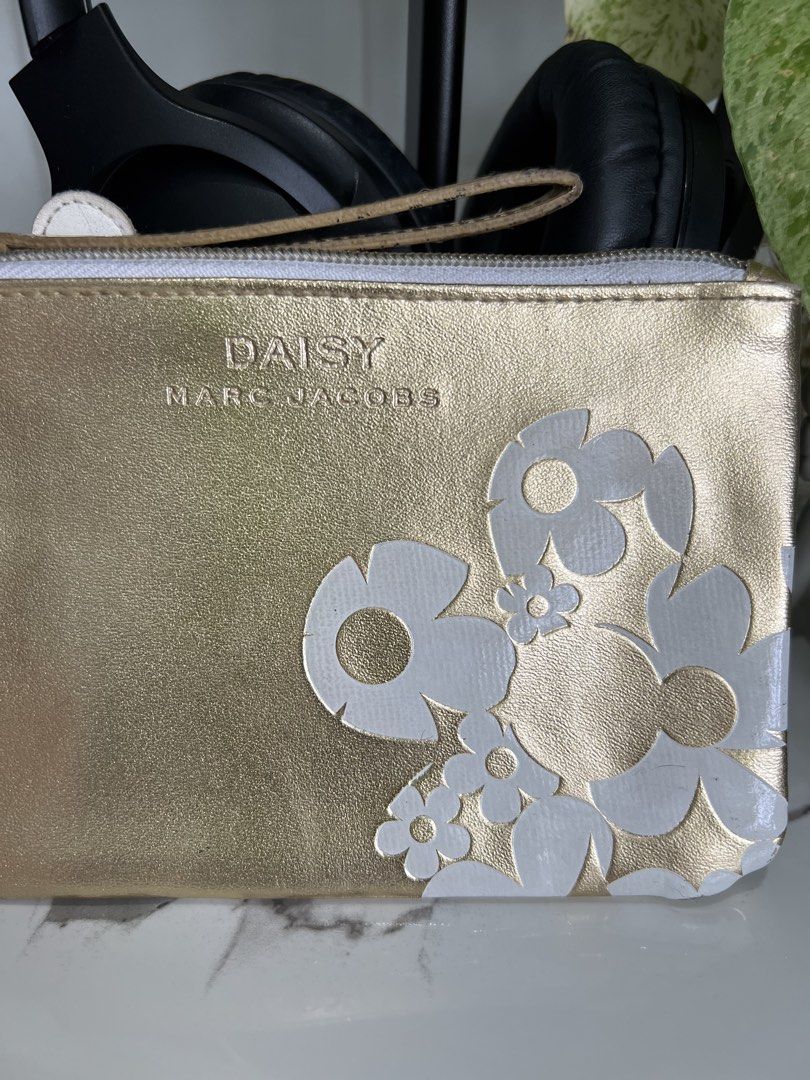 Marc Jacobs Daisy Gold Pouch (Category: Luxury Bags & Wallets) located in Cavite. Submitted by slumbermanila (Listing ID 1421555543, Image 2). Description: with stained in lining part Gold pouch with white daisy flower design. Features a wrist strap and a zipper closure. The interior lining has some stains. The pouch is approximately 9 inches long and 6 inches wide. This is a pre-loved item sourced from thrift finds. Kindly manage expectations, a