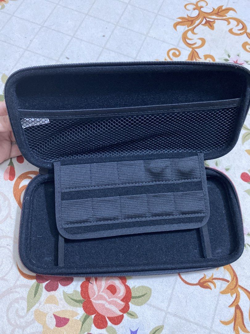 Nitendo Switch Oled Casing (Category: Cases & Covers) located in Klang. Submitted by maiza_ (Listing ID 1421461994, Image 2). Description: - Black carrying case - Features a handle for easy carrying - Secure zippered closure - Includes a mesh pocket - Compartment with elastic straps - Soft interior lining - Designed to protect and organize items Postage: RM 8 SM/ RM12 SS.