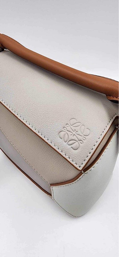 Inspired Loewe Puzzle Bag Mini (Category: Luxury Bags & Wallets) located in Manila. Submitted by marissagal.mendoza (Listing ID 1421656575, Image 2). Description: 👜 LOEWE PUZZLE MINI BAG ✨ Timeless. Architectural. Iconic. Brand: Loewe Model: Puzzle Condition: Very Good (pre-loved) Color: Light neutral with tan leather trim Hardware: Gold-tone Inclusion: Bag & strap only (no receipt) - Made in Spain - with BOX - with generic dust bag (pero try ko